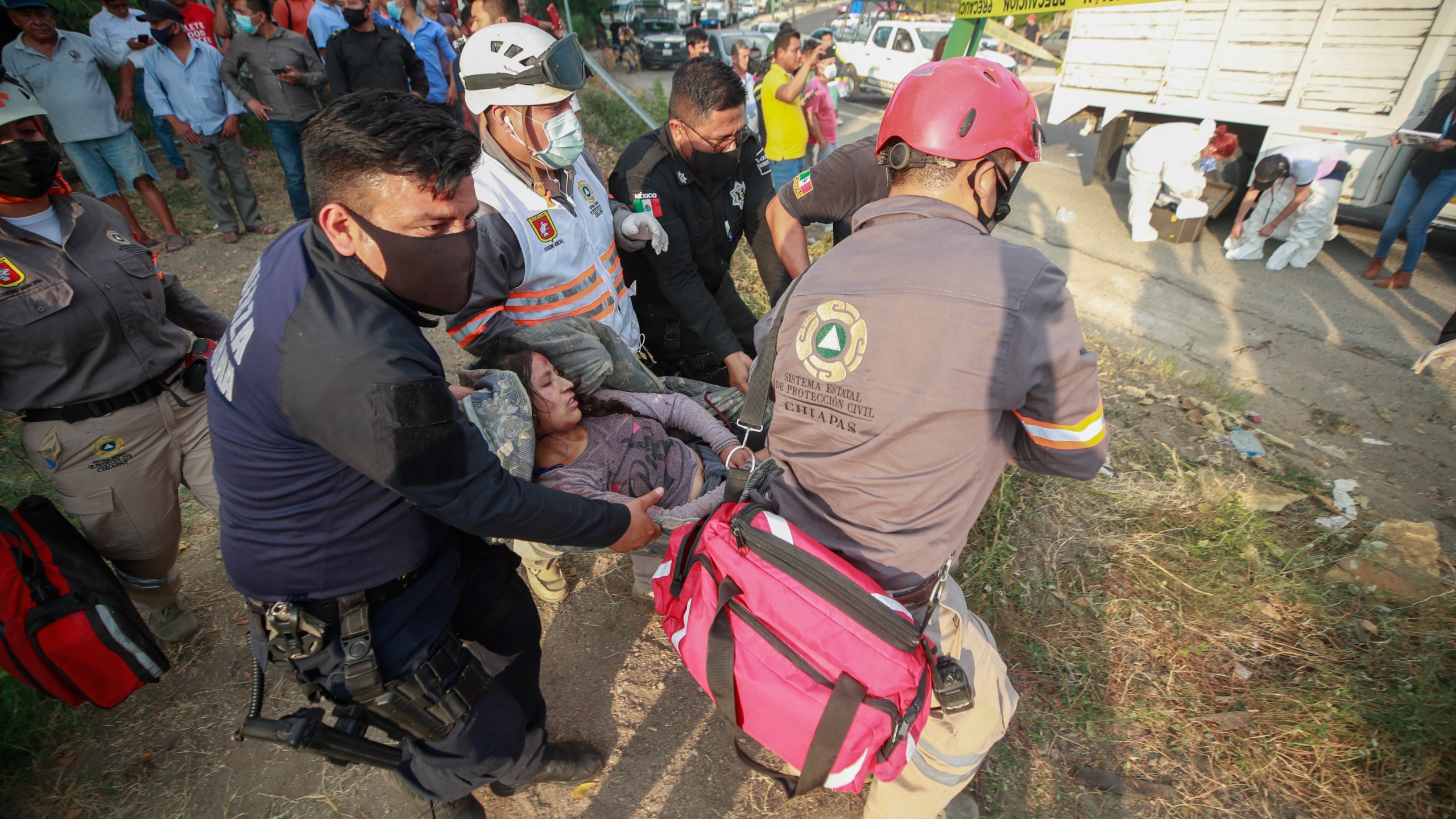 An injured migrant woman is moved by rescue personnel from the site of an accident near Tuxtla Gutierrez, Chiapas state, Mexico on Dec. 9, 2021. (AP Photo)