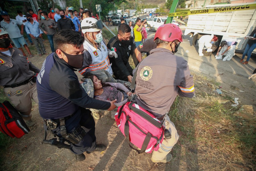 An injured migrant woman is moved by rescue personnel from the site of an accident near Tuxtla Gutierrez, Chiapas state, Mexico on Dec. 9, 2021. (AP Photo)