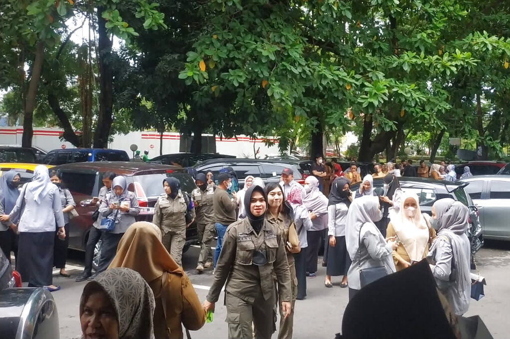 People wait outside after evacuating a government building following an earthquake in Makassar, South Sulawesi, Indonesia, Tuesday, Dec. 14, 2021. (AP Photo/Daeng Mansur)