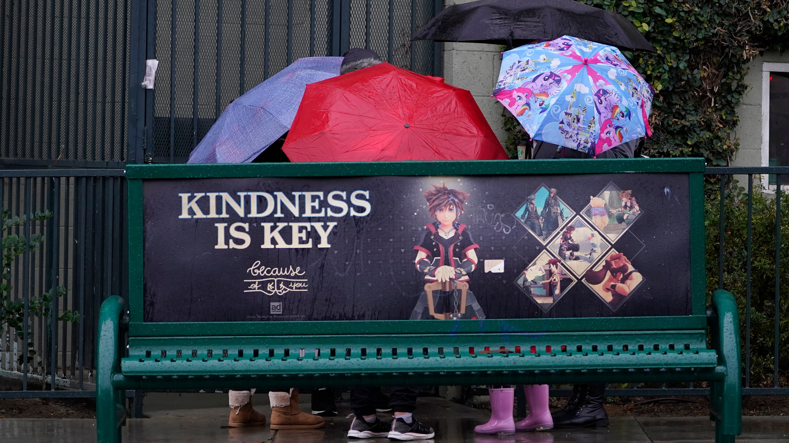 People huddle under their umbrellas at a bus stop downtown Los Angeles on Dec. 14, 2021. (Damian Dovarganes/Associated Press)