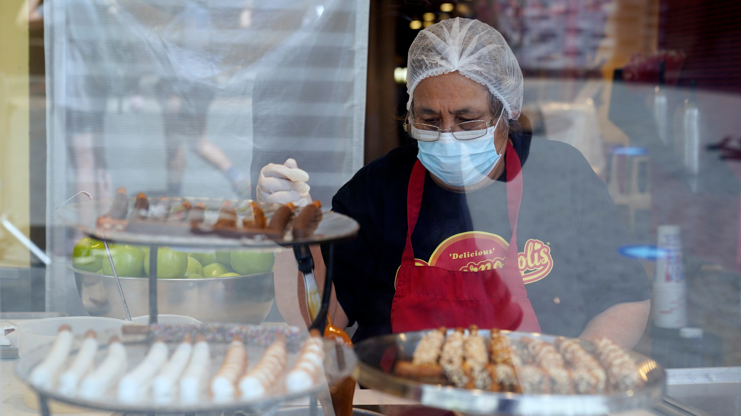 A worker wears a mask while preparing desserts at the Universal City Walk Friday, May 14, 2021, in Universal City, Calif. Workplace regulators are poised on Thursday, Dec. 16 to extend California’s coronavirus pandemic regulations into next year with some revisions that business groups say could worsen the labor shortage. (AP Photo/Marcio Jose Sanchez, File)