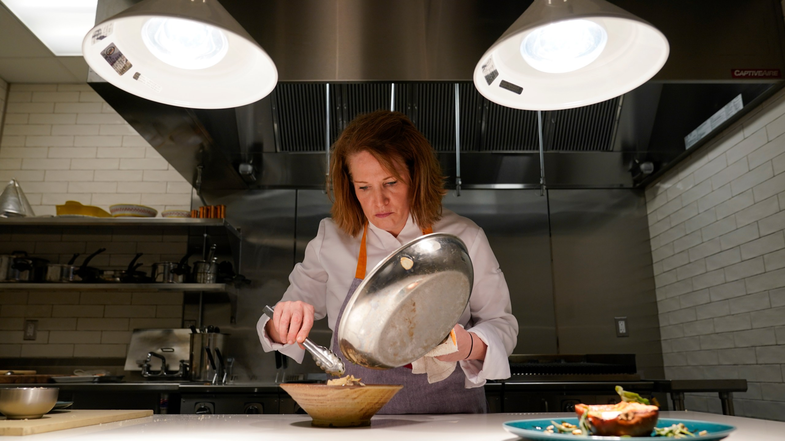 Amy Brandwein, chef and owner of Centrolina, prepares a dish in her restaurant kitchen, Thursday, Dec. 16, 2021, in Washington. While restaurants in the U.S. and United Kingdom are open without restrictions and often bustling, they are entering their second winter of the coronavirus pandemic anxious about what’s ahead. (AP Photo/Patrick Semansky)