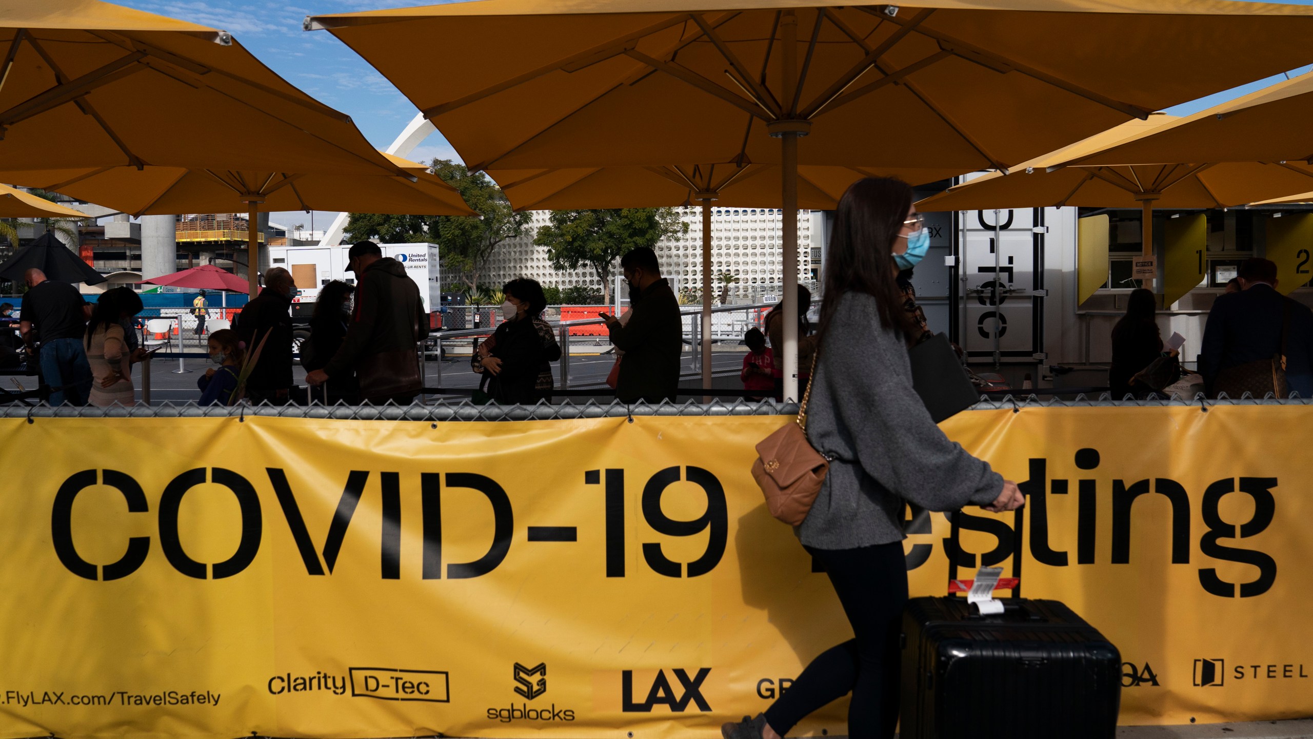 Travelers wait in line to get tested for COVID-19 at Los Angeles International Airport in Los Angeles, Monday, Dec. 20, 2021. (AP Photo/Jae C. Hong)