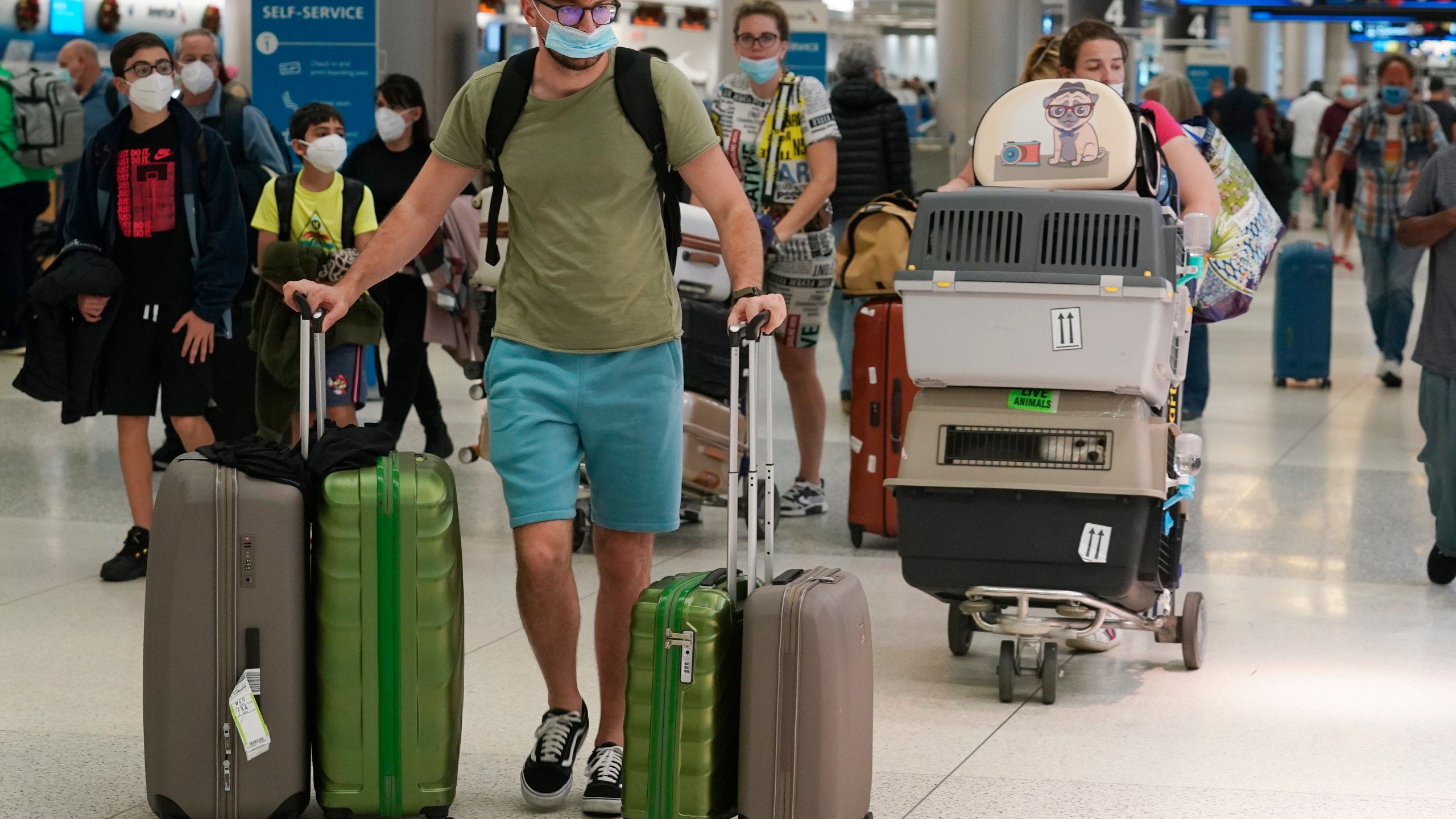 A family and their pets walk through Miami International Airport on Dec. 20, 2021, in Miami. Public health officials are urging caution as the new omicron variant might become the dominant strain in the U.S. during the holiday break. (AP Photo/Marta Lavandier)