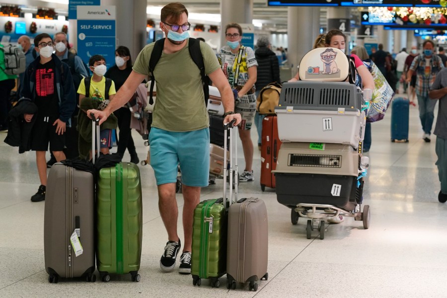 A family and their pets walk through Miami International Airport on Dec. 20, 2021, in Miami. Public health officials are urging caution as the new omicron variant might become the dominant strain in the U.S. during the holiday break. (AP Photo/Marta Lavandier)