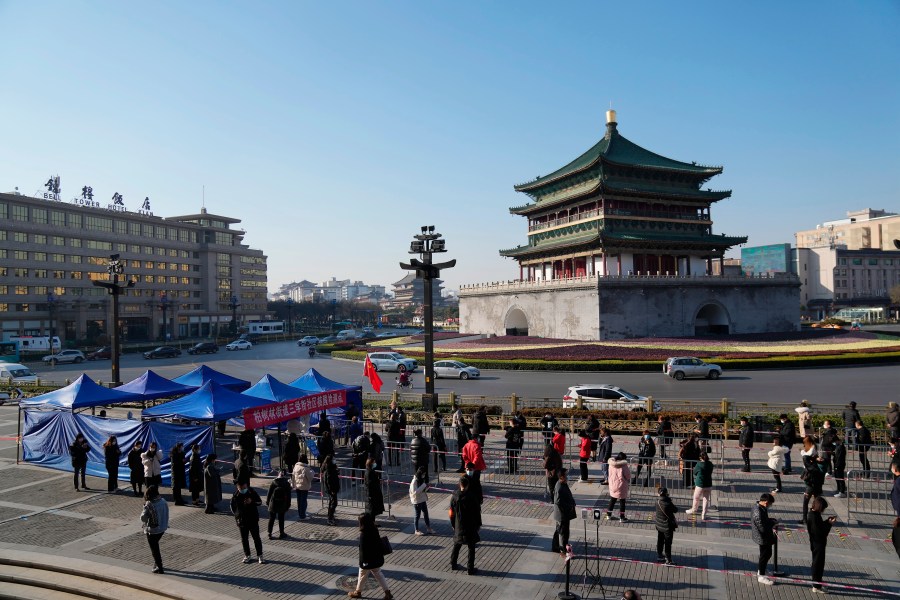 In this photo released by China's Xinhua News Agency, residents line up for tests at a COVID-19 testing site in Xi'an in northwestern China's Shaanxi Province, Tuesday, Dec. 21, 2021. China on Wednesday ordered millions of people locked down in neighborhoods and workplaces in the northern city of Xi'an following a spike in coronavirus cases. (Li Yibo/Xinhua via AP)