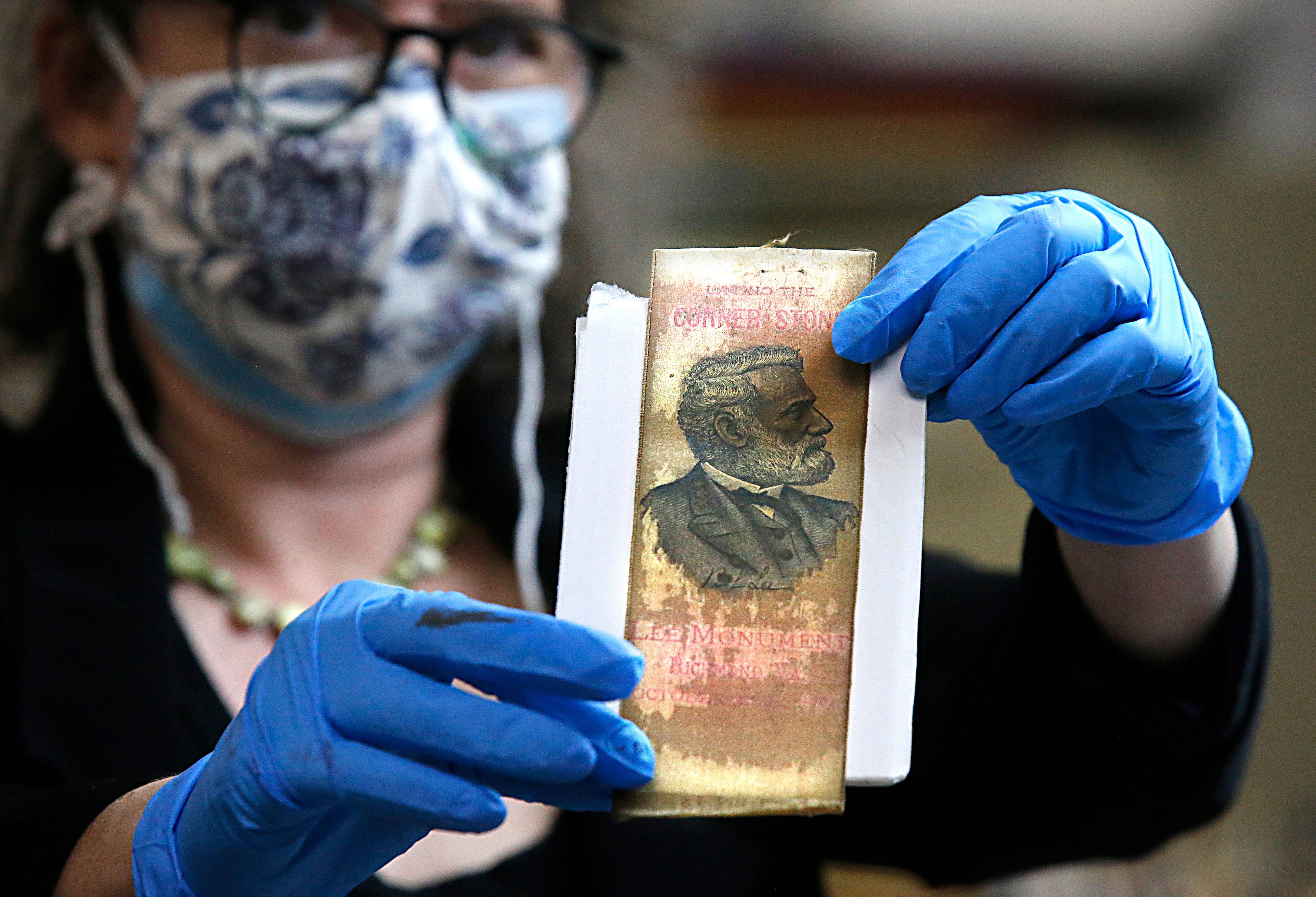 Gretchen Guidess holds up a ribbon with the likeness of Robert E. Lee, which was one of the artifacts inside the copper box time capsule recovered from the base of the Robert E. Lee monument, Tuesday, Dec. 28, 2021, at the Virginia Department of Historical Resources lab in Richmond, Va. (Bob Brown/Richmond Times-Dispatch via AP)