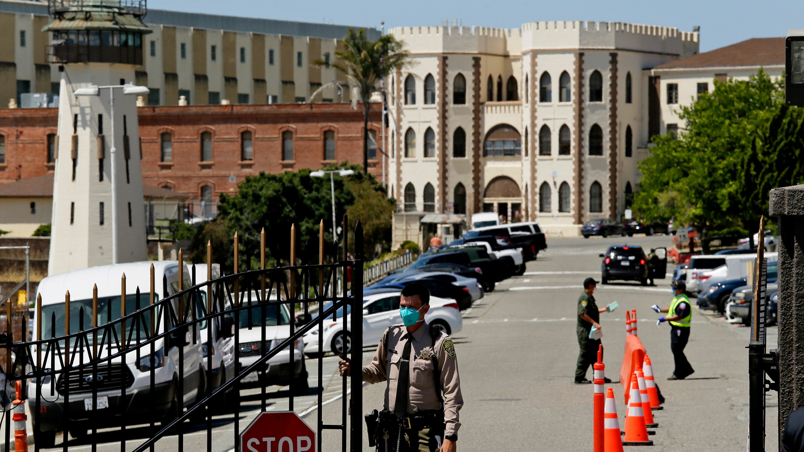 In this July 9, 2020, file photo, a correctional officer closes the main gate at San Quentin State Prison in San Quentin, Calif. With a new and more infectious coronavirus variant sweeping California, attorneys representing inmates say violations of health orders by prison staff risk a repeat of the outbreaks that killed dozens in the first year of the pandemic. Gov. Gavin Newsom's administration is fighting a federal judge's order that all California prison workers must be vaccinated against the coronavirus or have a religious or medical exemption. (AP Photo/Eric Risberg, File)