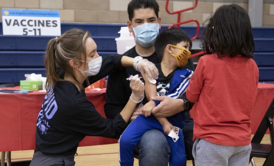 Aidan Williams sits with son Ocean, 5, as he gets a COVID-19 vaccine shot from nurse Chelsea Meyer in November.(Myung J. Chun/Los Angeles Times)