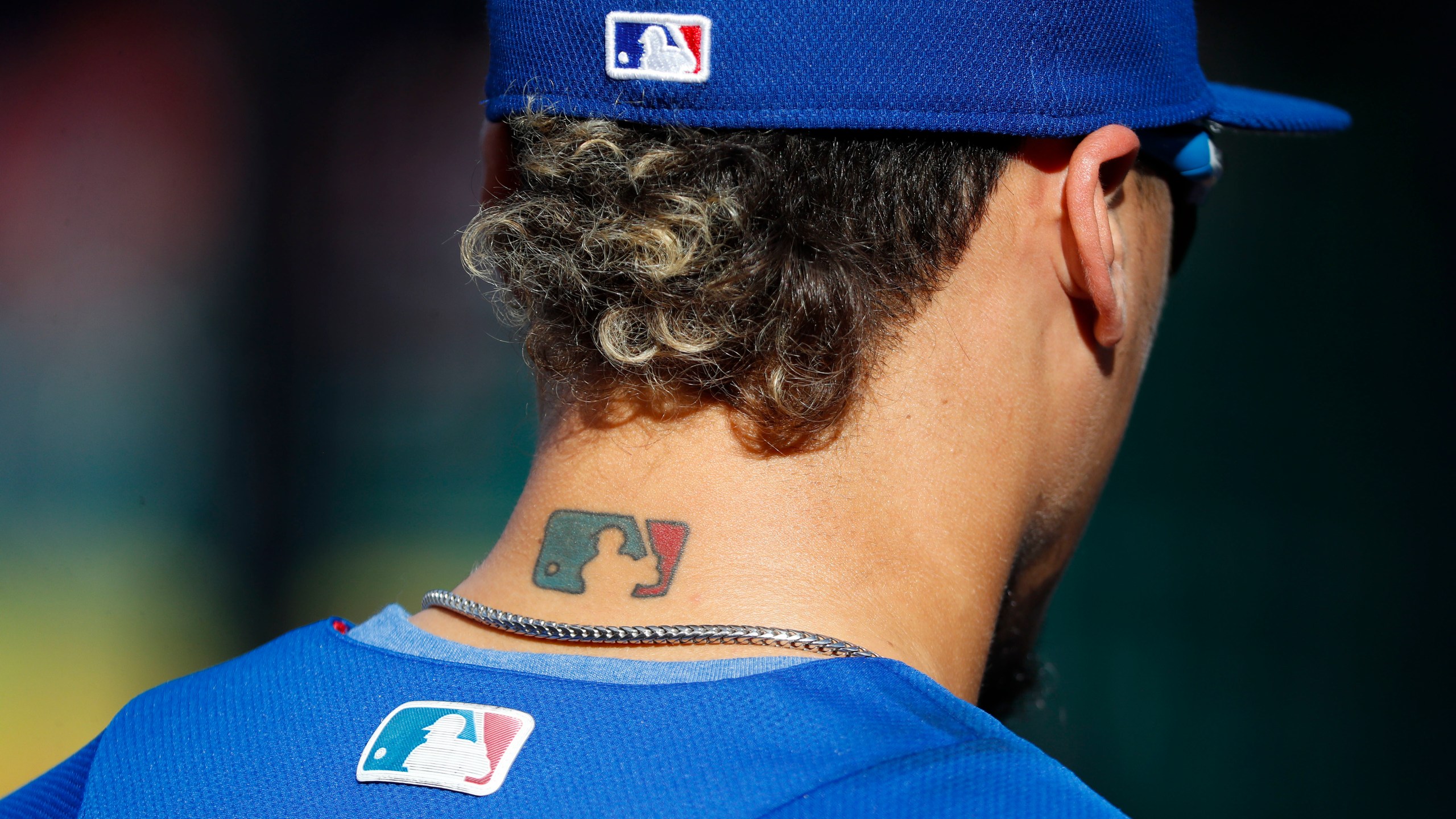 Then-Chicago Cubs' Javier Baez sports an MLB logo tattoo and logos on his hat and jersey as he waits to take batting practice before Game 2 of baseball's National League Division Series against the Washington Nationals at Nationals Park, Saturday, Oct. 7, 2017, in Washington. The clock ticked down toward the expiration of Major League Baseball’s collective bargaining agreement at 11:59 p.m. EST Wednesday night, Dec. 1, 2021, and what was likely to be a management lockout ending the sport’s labor peace at over 26 1/2 years. (AP Photo/Pablo Martinez Monsivais, File)