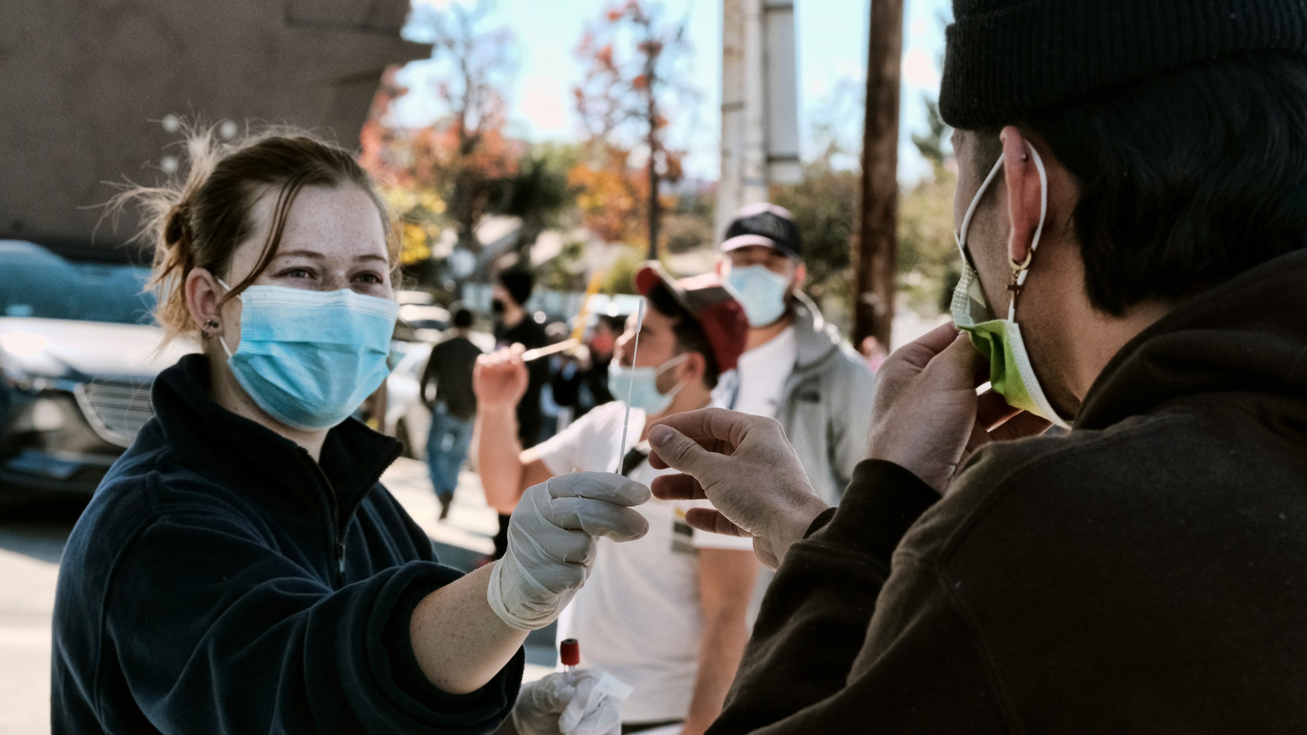 A man is handed a swab for a Covid-19 rapid test as people line up at a gas station in the Reseda section of Los Angeles on Sunday, Dec. 26, 2021. (AP Photo/Richard Vogel)