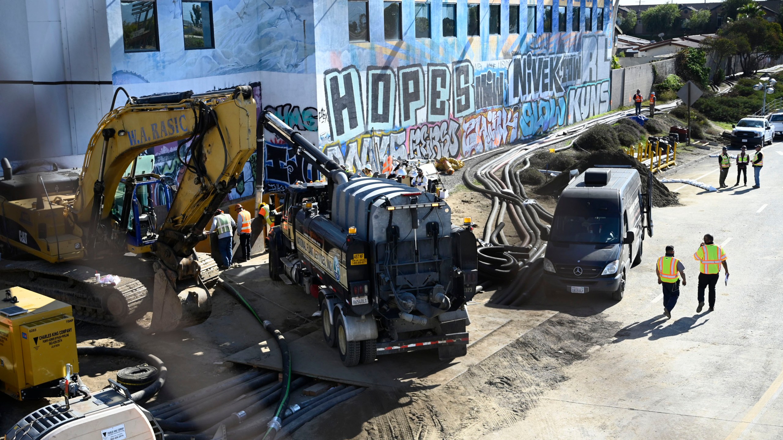 Crews work on the pipe break that caused a sewage spill this past week in Carson, Calif., on Jan. 3, 2022. Temporary pipes are detouring the sewage about 1,000 feet while repairs are made on the line. (Brittany Murray/The Orange County Register via AP)