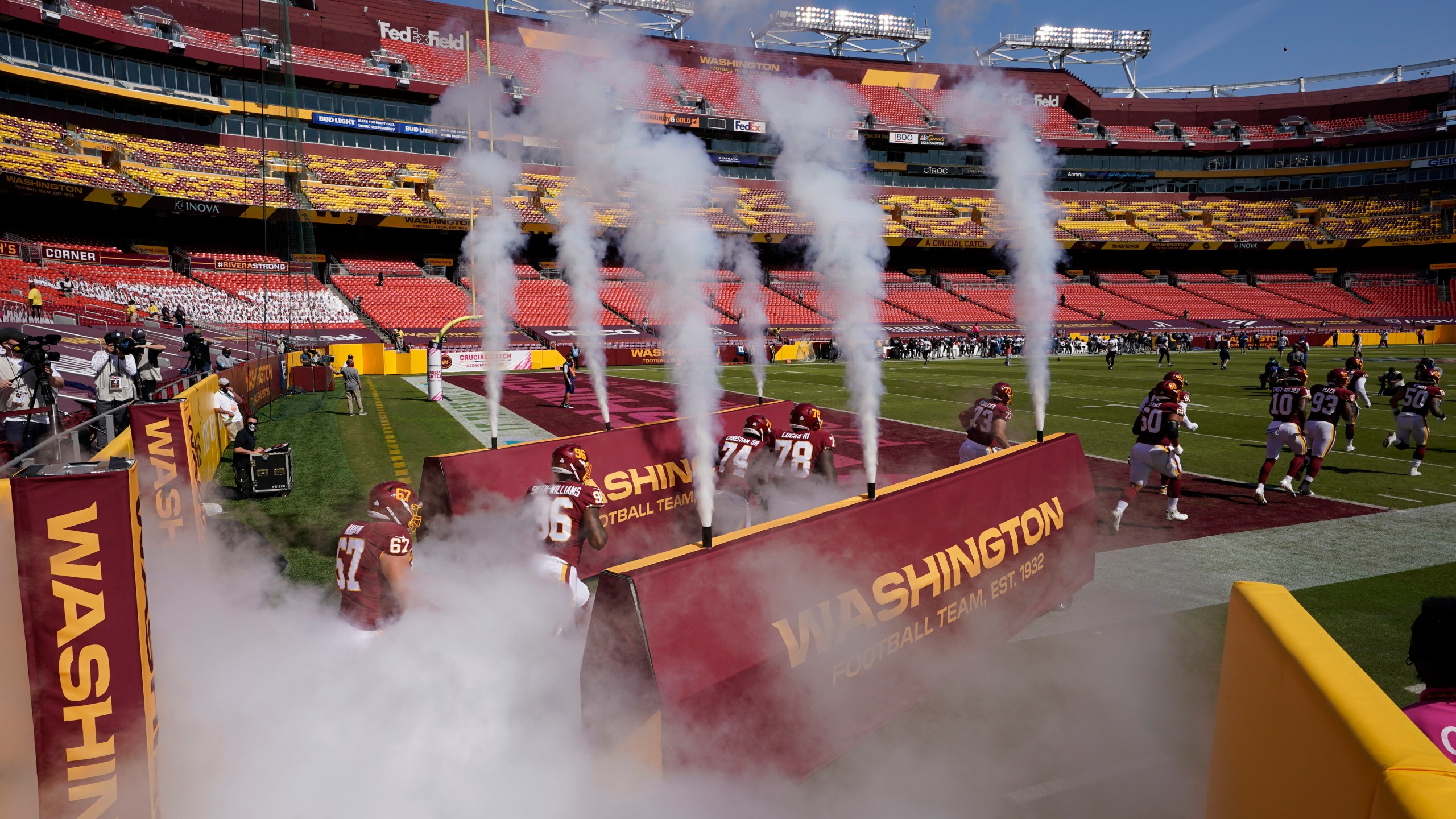 Washington Football team players run into an empty stadium prior to the start of the Baltimore Ravens at Washington Football Team NFL football game on Oct. 4, 2020, in Landover, Md. (Steve Helber/Associated Press)