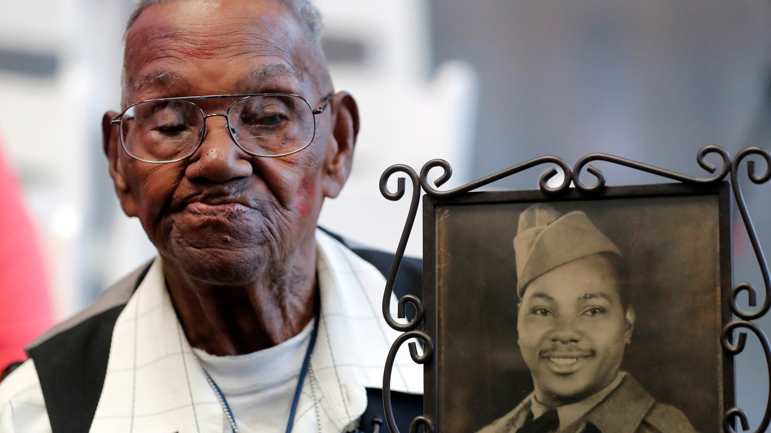 World War II veteran Lawrence Brooks holds a photo of him taken in 1943, as he celebrates his 110th birthday at the National World War II Museum in New Orleans, on Sept. 12, 2019. Brooks, the oldest World War II veteran in the U.S. — and believed to be the oldest man in the country — died on Wednesday, Jan. 5, ,2022 at the age of 112. (AP Photo/Gerald Herbert, File)