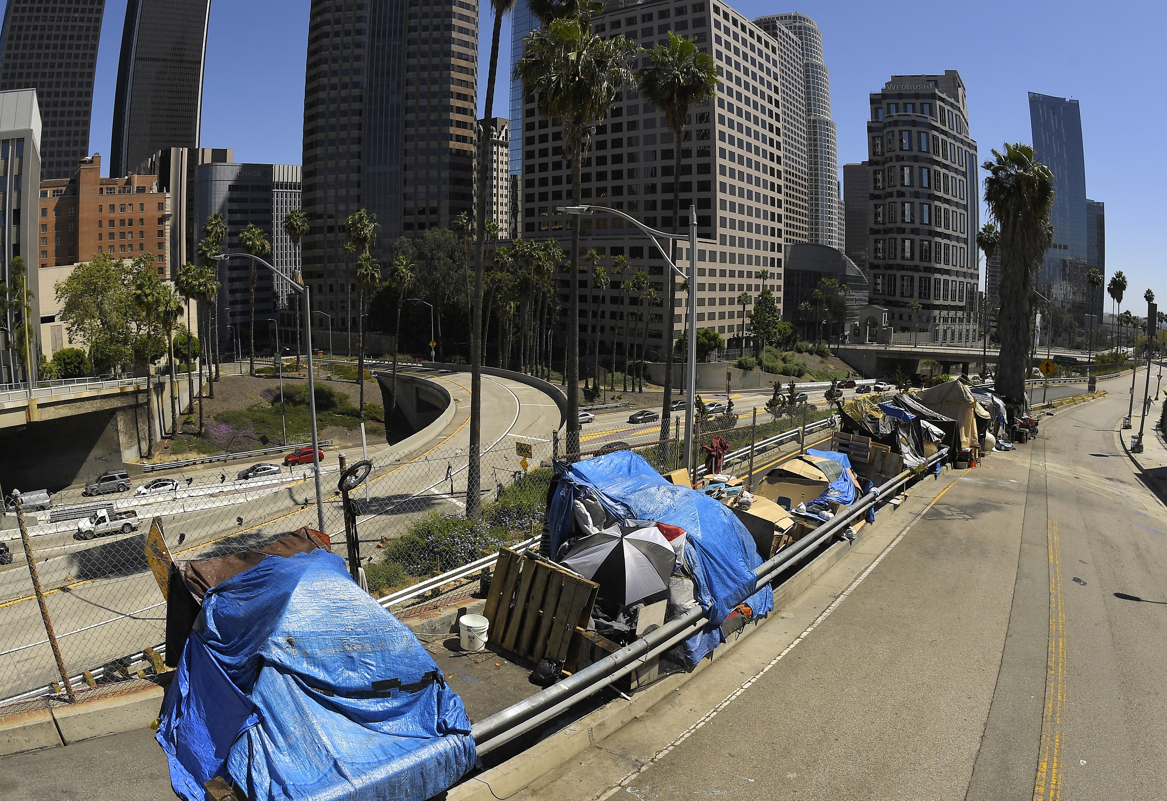 This May 21, 2020, file photo, shows a homeless encampment on Beaudry Avenue as traffic moves along Interstate 110 below during the coronavirus outbreak, in downtown Los Angeles.(AP Photo/Mark J. Terrill, File)