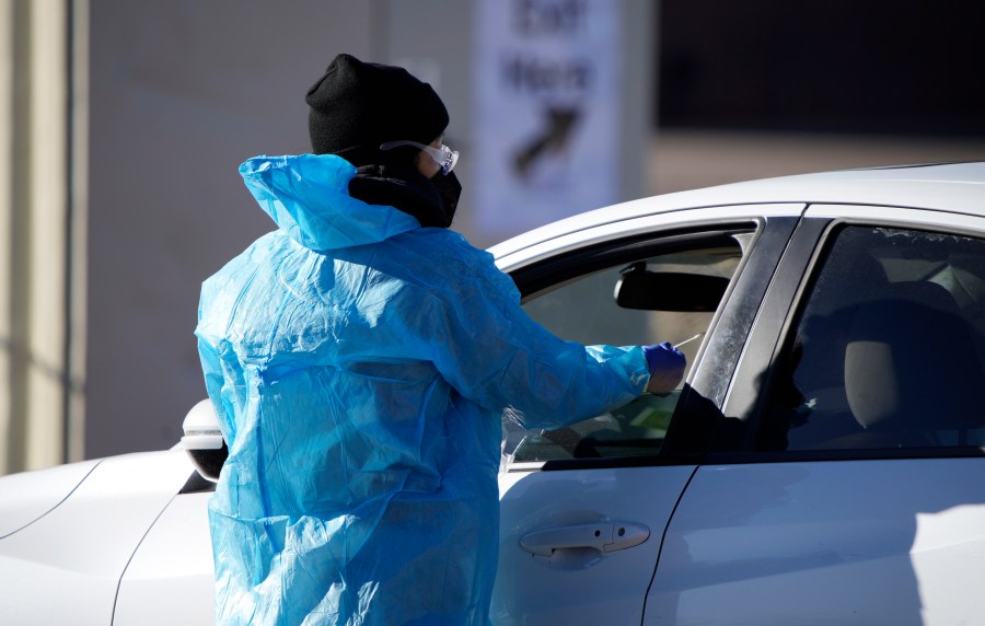 A medical technician performs a nasal swab test on a motorist queued up in a line at a COVID-19 testing site near All City Stadium Dec. 30, 2021, in southeast Denver. (AP Photo/David Zalubowski, File)