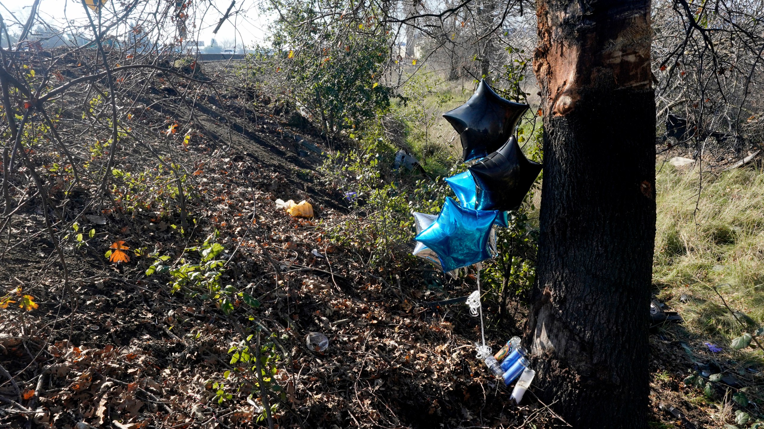 A small memorial marks the scene, Wednesday, Jan. 19, 2022, were the body of a woman was found inside a car that had crashed off Interstate 80 in Sacramento, Calif. A caller to the California Highway Patrol on Tuesday, Jan. 18, reported seeing a vehicle in a ditch just off the onramp to westbound I-80 from West El Camino Ave. Woodland police confirmed the woman found in the car was the same woman reported missing to them on Monday. (AP Photo/Rich Pedroncelli)