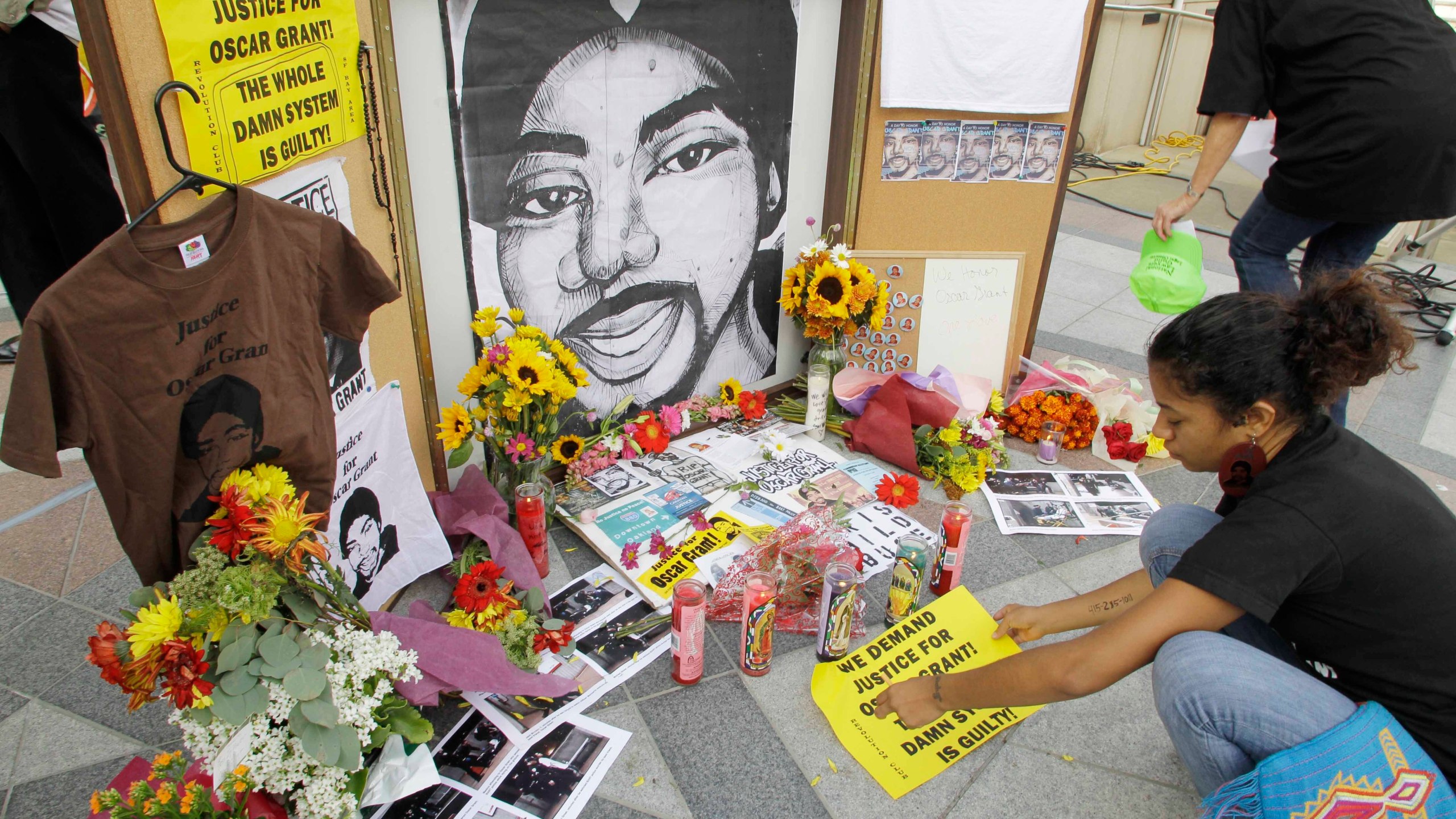 A woman leaves a sign at a make-shift memorial for Oscar Grant after the sentencing of former Bay Area Rapid Transit police officer Johannes Mehserle in Oakland, Calif., Friday, Oct. 5, 2010. Mehserle claimed he had thought he had drawn his Taser rather than his gun when he shot Grant at a BART station on Jan. 1, 2009. Lawmakers approved a bill on Monday, Jan. 31, 2022, by Assemblyman Tom Lackey, R-Palmdale, that would require officers to carry their primary weapon and Taser on opposite sides of their bodies to deter confusion. (AP Photo/Paul Sakuma, File)