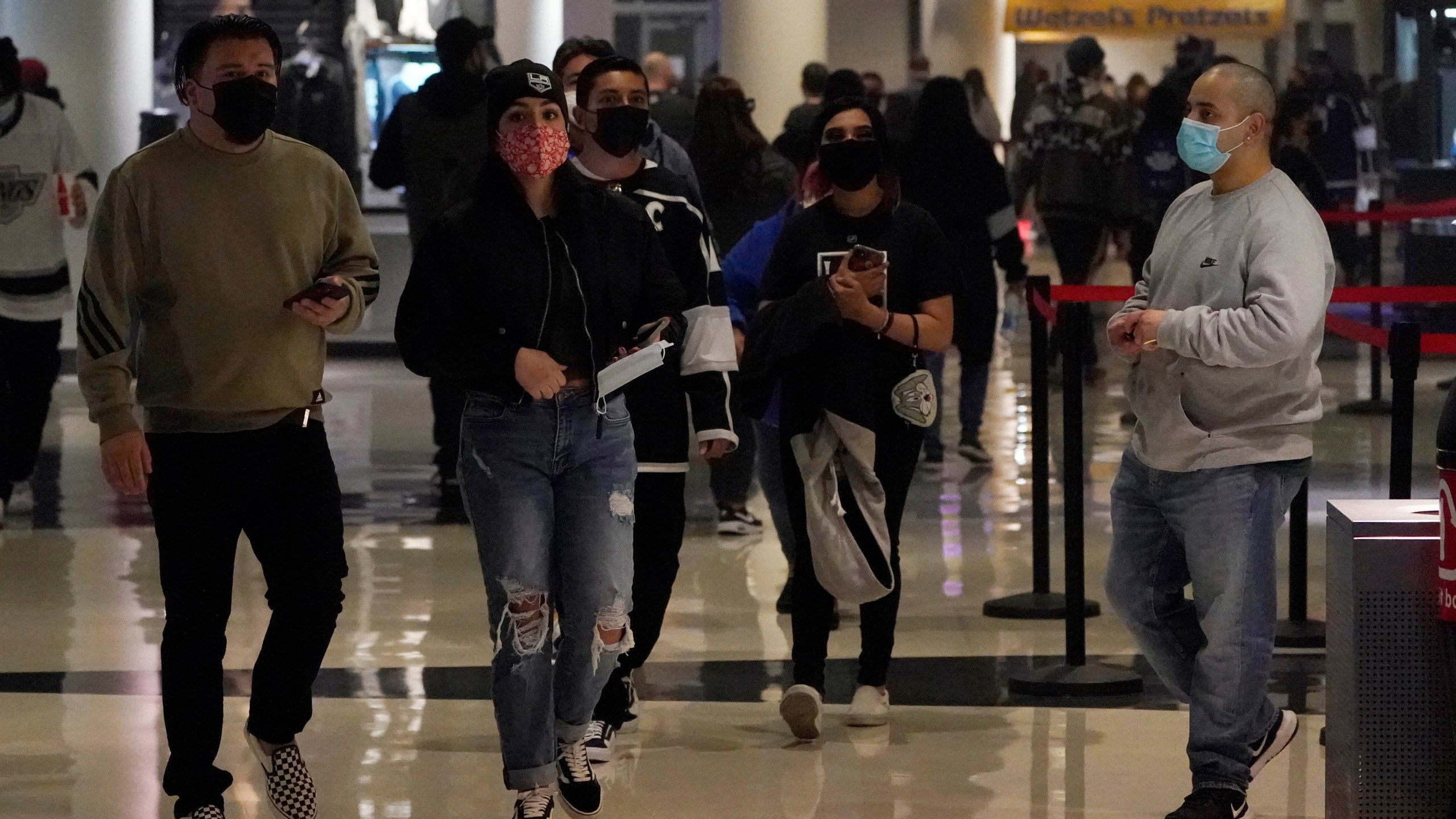 Fans wear masks as they walk inside crypto.com Arena before an NHL hockey game between the Los Angeles Kings and the Nashville Predators Thursday, Jan. 6, 2022, in Los Angeles. (AP Photo/Marcio Jose Sanchez)