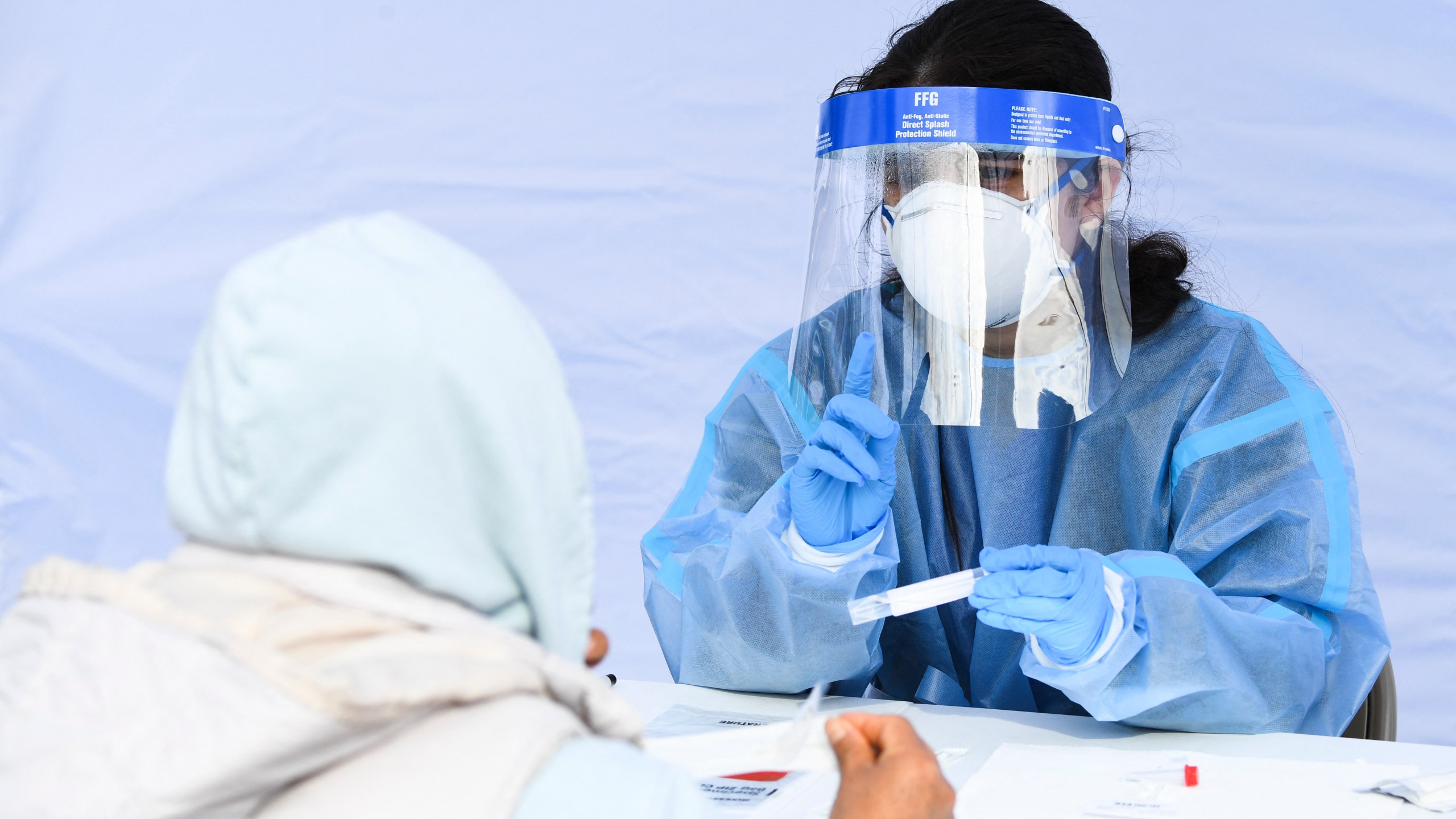 A healthcare worker gives instructions to a person on how to swab their nose as they receive testing for both rapid antigen and PCR COVID-19 tests at a Reliant Health Services testing site in Hawthorne on Jan. 18, 2022. (Patrick T. FALLON / AFP via Getty Images)