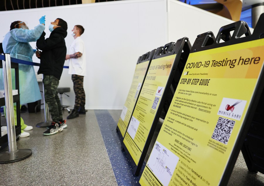 Merline Jimenez (L) administers a COVID-19 nasopharyngeal swab to a person at a testing site located in the international terminal at Los Angeles International Airport amid a surge in omicron variant cases on Dec. 21, 2021. (Mario Tama/Getty Images)