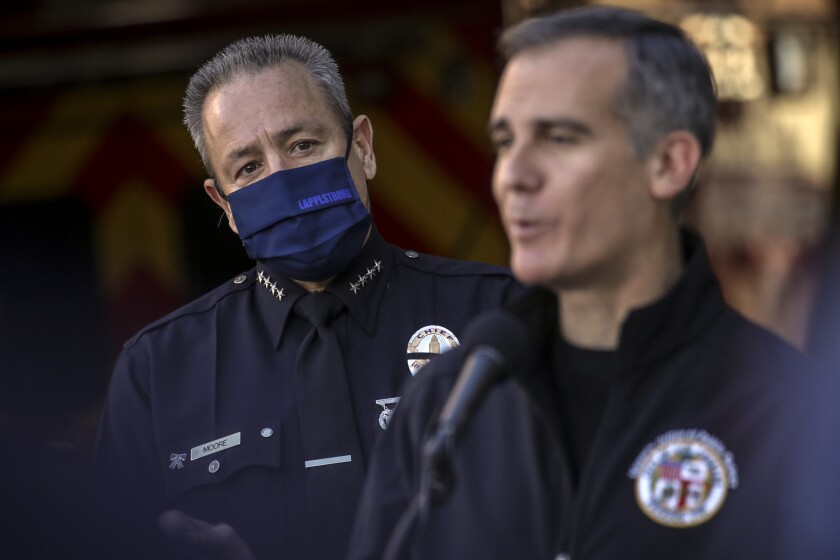 LAPD Chief Moore, left, watches as Mayor Eric Garcetti discusses coronavirus infections among public safety workers on Jan. 6, 2021. Both have backed the city’s vaccine mandate.(Irfan Khan / Los Angeles Times)