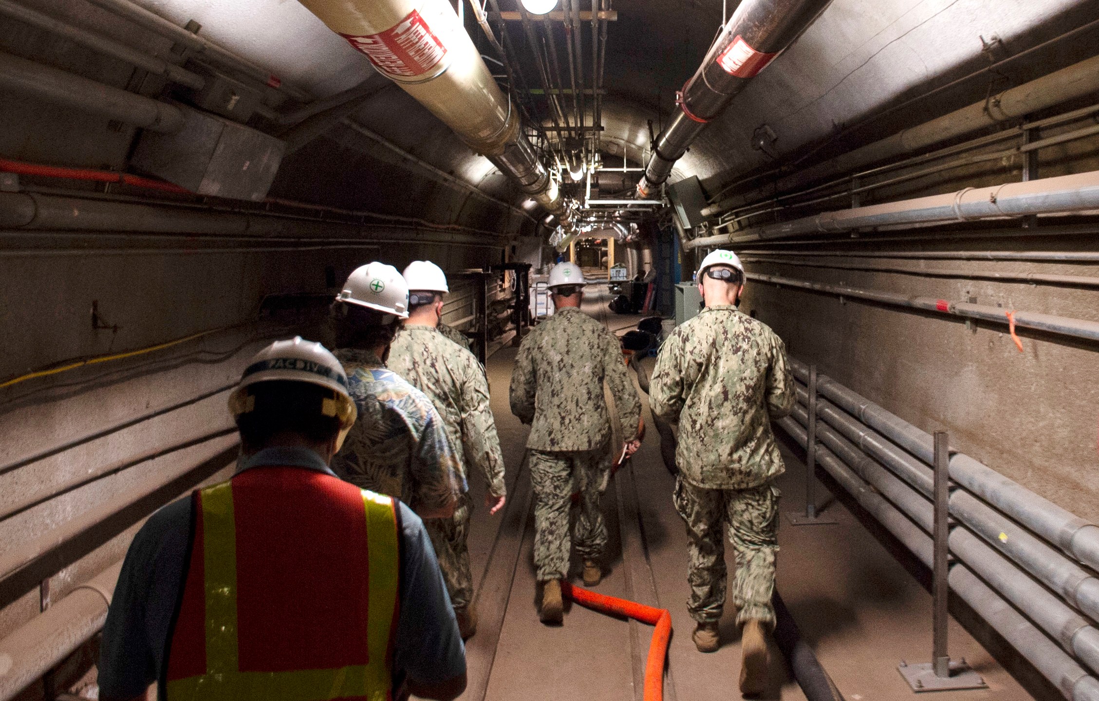 In this Dec. 23, 2021, photo provided by the U.S. Navy, Rear Adm. John Korka, Commander, Naval Facilities Engineering Systems Command (NAVFAC), and Chief of Civil Engineers, leads Navy and civilian water quality recovery experts through the tunnels of the Red Hill Bulk Fuel Storage Facility, near Pearl Harbor, Hawaii. The Navy is scrambling to contain what one lawmaker has called a "crisis of astronomical proportions" after jet fuel leaked from an 80-year-old Hawaii tank farm, seeped into a drinking water well and polluted the water streaming out of faucets in Pearl Harbor military housing. (Mass Communication Specialist 1st Class Luke McCall/U.S. Navy via AP)