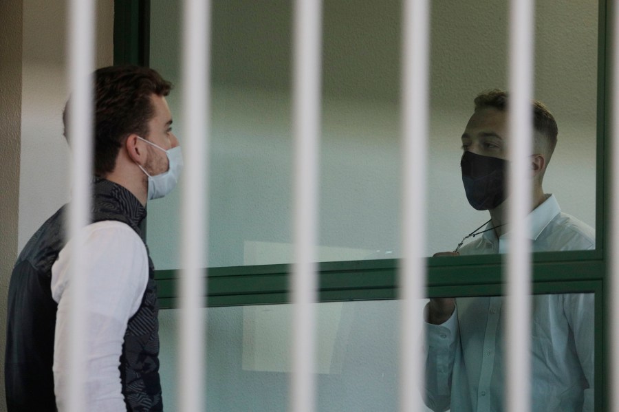 Finnegan Lee Elder, right, shows a crucifix to co-defendant Gabriel Natale-Hjorth before a jury began deliberating their fate on May 5, 2021. (Gregorio Borgia/Associated Press)