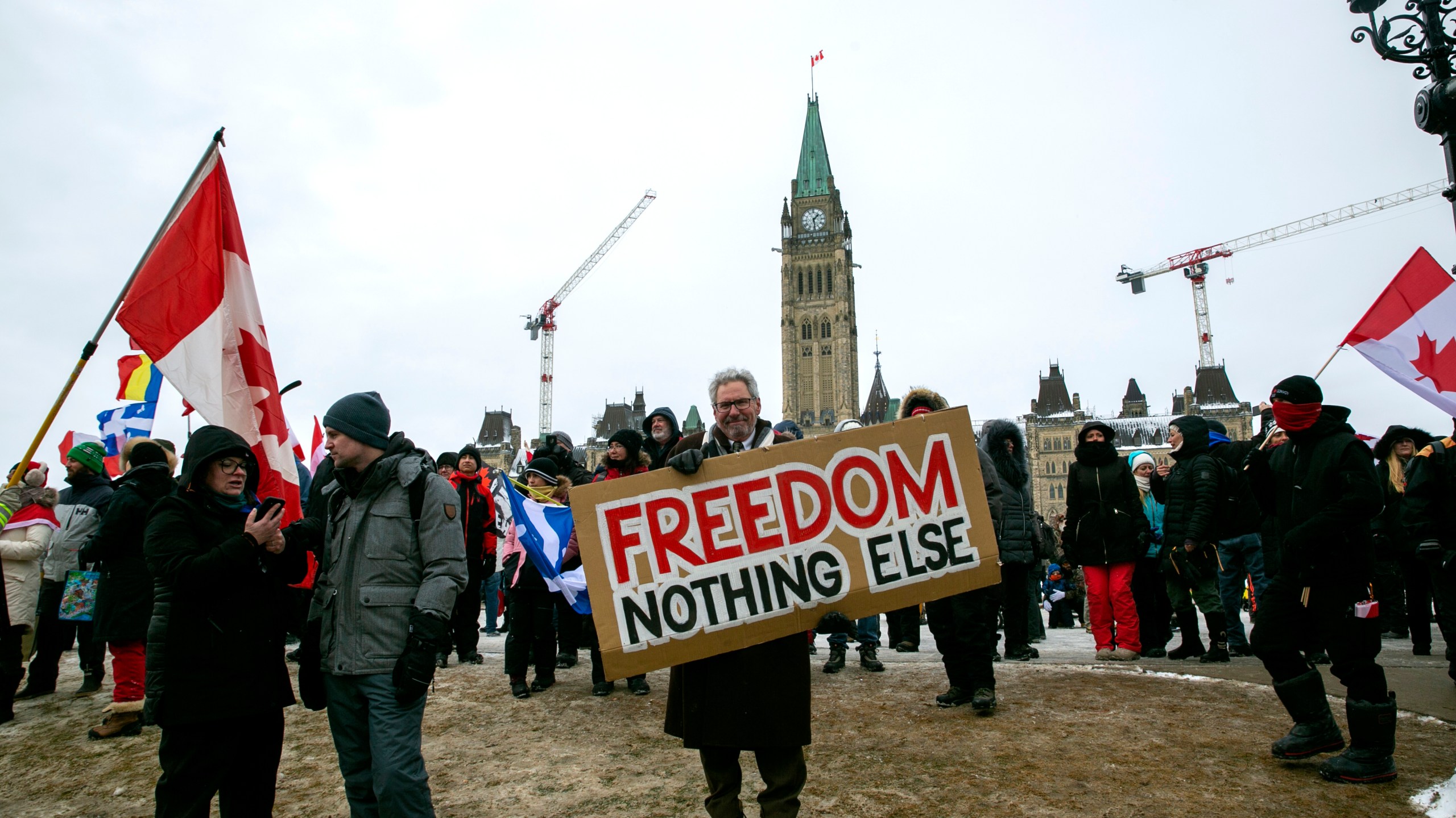 Don Stephens, 65, a retired graphic designer, holds a sign on Parliament Hill to support trucks lined up in protest of COVID-19 vaccine mandates and restrictions in Ottawa, Ontario, on Saturday, Feb. 12, 2022. Stephens said he’s come into Ottawa twice to show support for protesters there. He views them as representatives of a “silent majority that had been longing to have their voice heard.” (AP Photo/Ted Shaffrey)