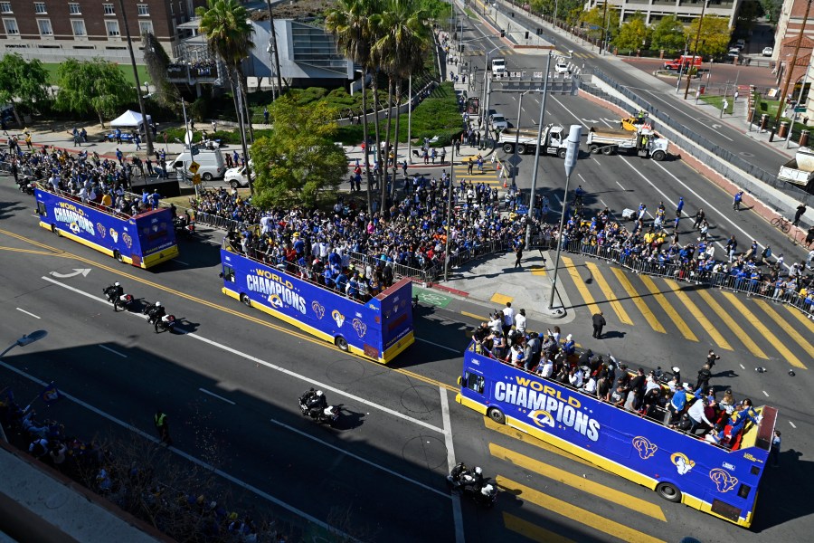 Buses carrying Los Angeles Rams players and coaches drive past fans during the team's victory parade in Los Angeles, Wednesday, Feb. 16, 2022, following their win Sunday over the Cincinnati Bengals in the NFL Super Bowl 56 football game. (AP Photo/Kyusung Gong)