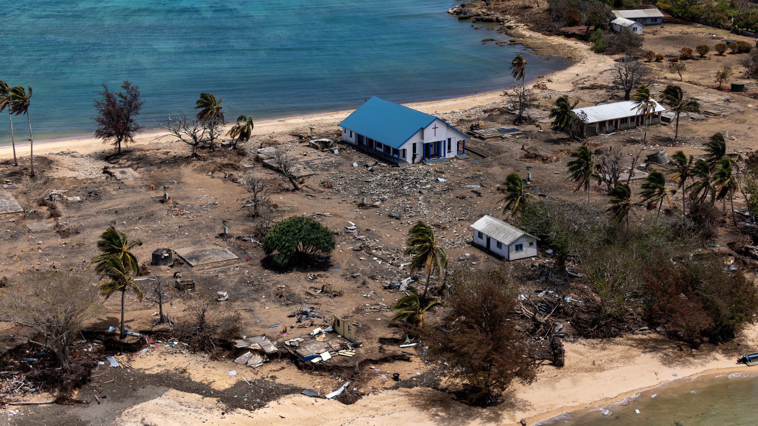 In this photo provided by the Australian Defence Force, debris from damaged building and trees are strewn around on Atata Island in Tonga, on Jan. 28, 2022, following the eruption of an underwater volcano and subsequent tsunami. (POIS Christopher Szumlanski/Australian Defence Force via AP, File)