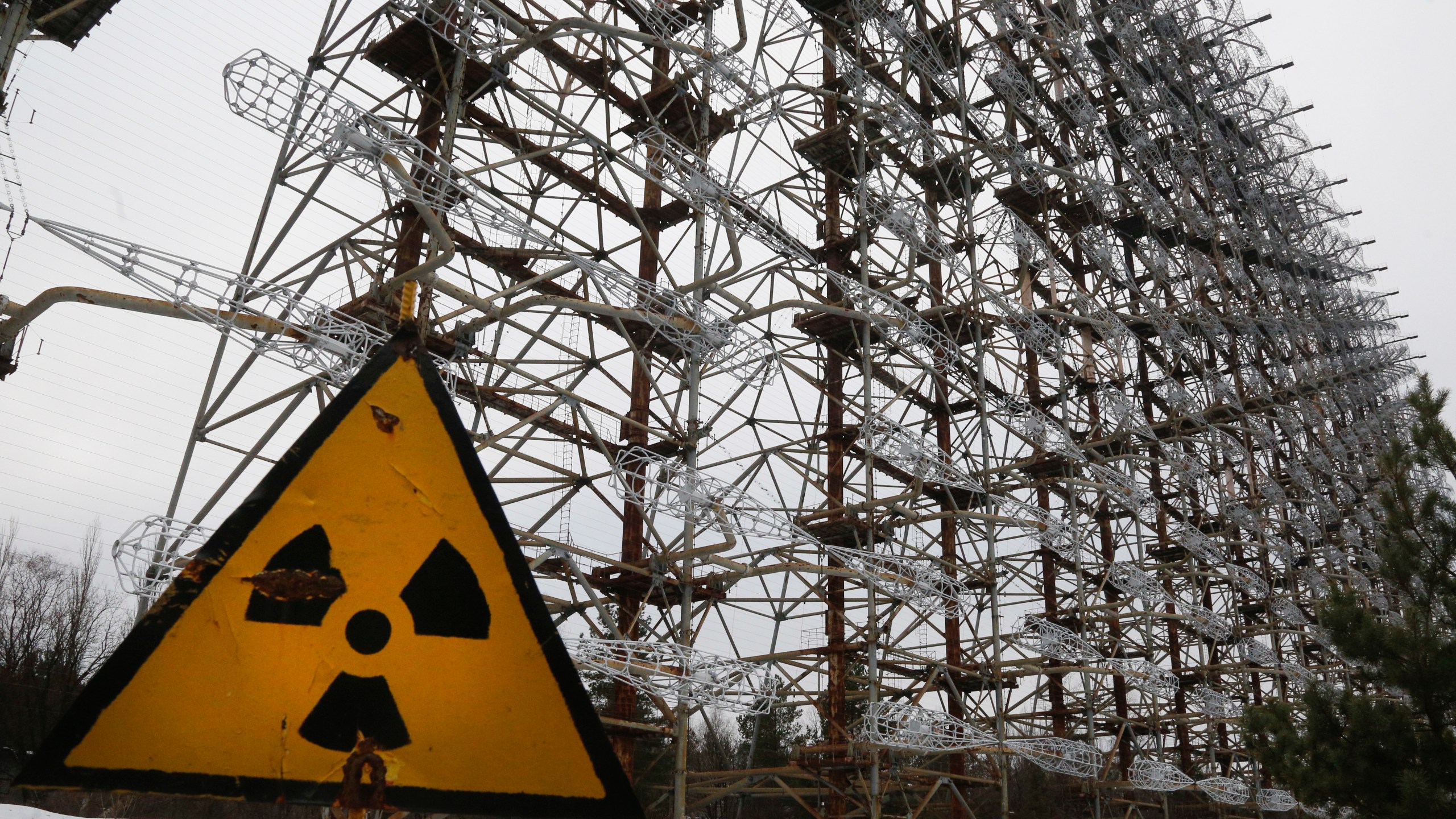 A Soviet-era top secret object Duga, an over-the-horizon radar system once used as part of the Soviet missile defense early-warning radar network, seen behind a radioactivity sign in Chernobyl, Ukraine, on Nov. 22, 2018. Among the most worrying developments on an already shocking day, as Russia invaded Ukraine on Thursday, was warfare at the Chernobyl nuclear plant, where radioactivity is still leaking from history's worst nuclear disaster 36 years ago. (AP Photo/Efrem Lukatsky, File)