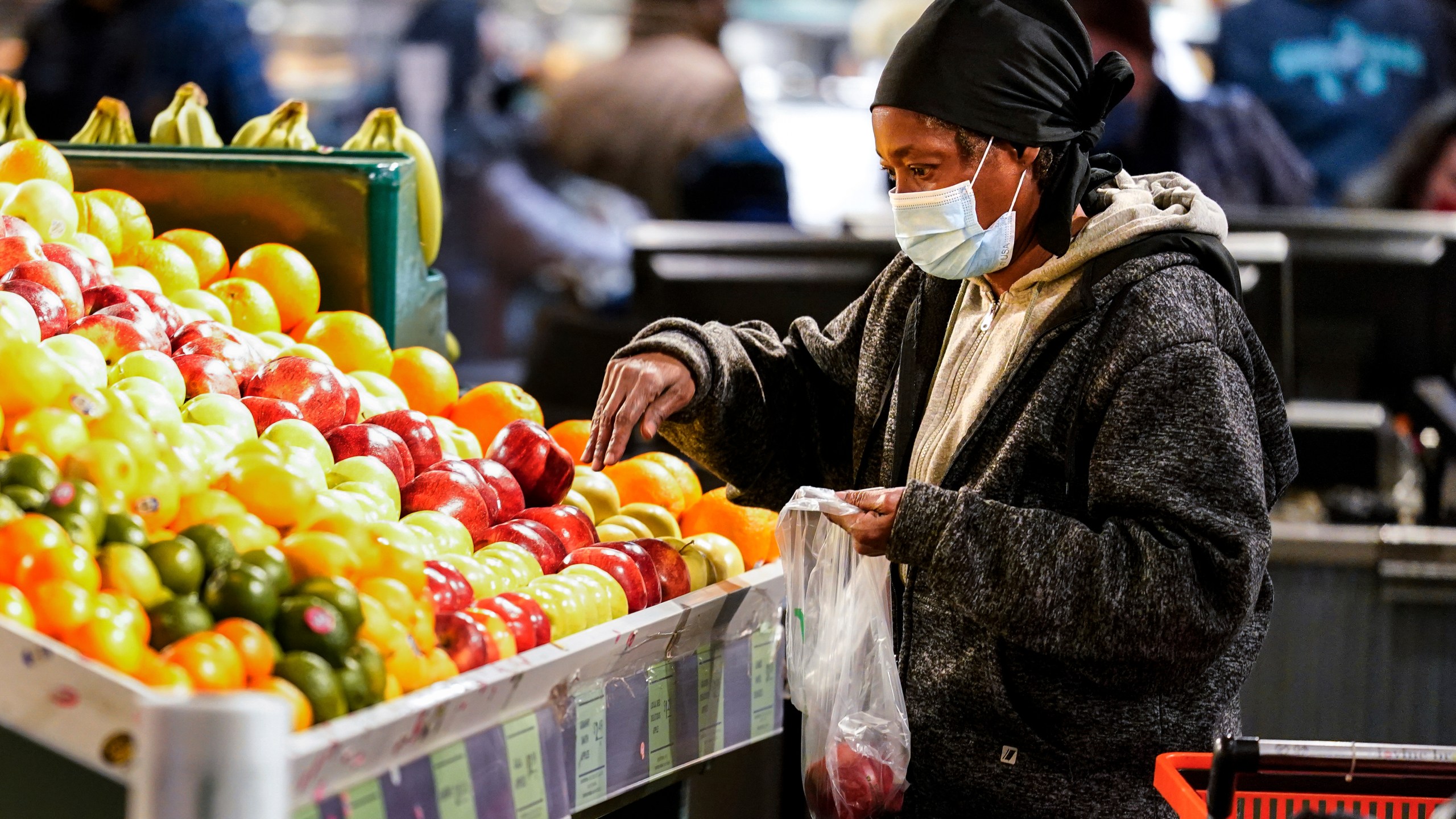 A shopper wearing a proactive mask as a precaution against the spread of the coronavirus selects fruit at the Reading Terminal Market in Philadelphia on Feb. 16, 2022. (AP Photo/Matt Rourke)