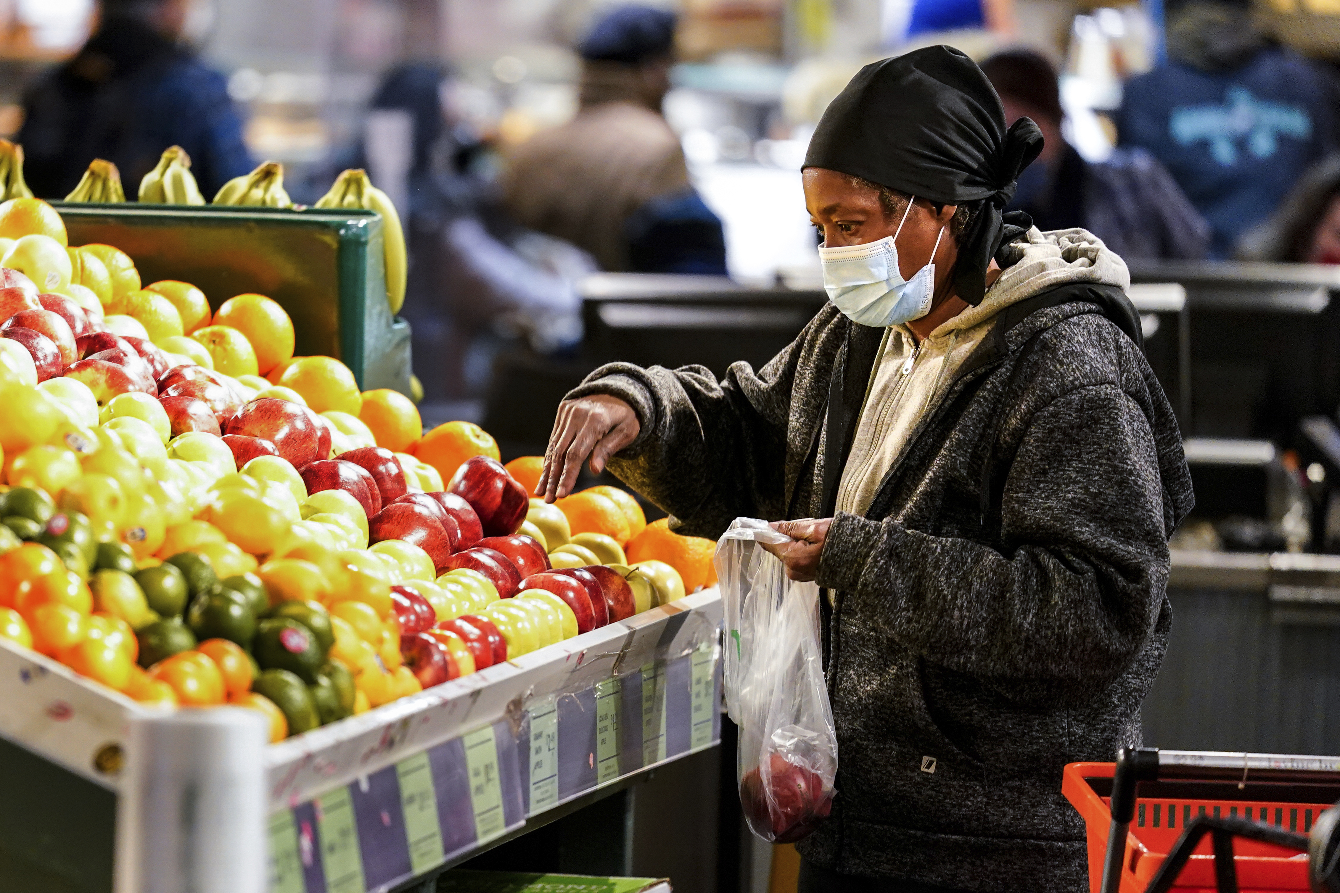 A shopper wearing a proactive mask as a precaution against the spread of the coronavirus selects fruit at the Reading Terminal Market in Philadelphia on Feb. 16, 2022. (AP Photo/Matt Rourke)