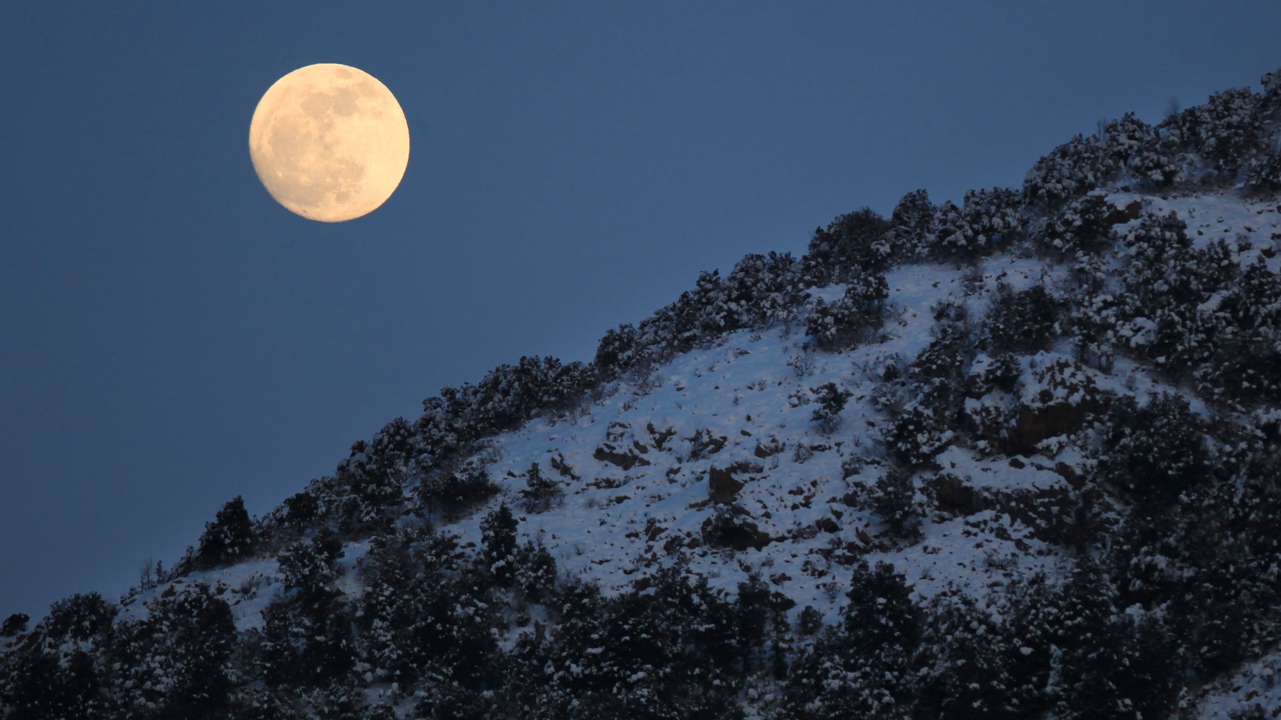 A picture taken on February 6, 2012 shows the moon behind snow covered landscape near the Corsican village of Bastelica. (PASCAL POCHARD-CASABIANCA/AFP via Getty Images)