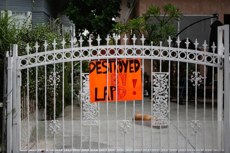 A sign reading “Destroyed by LAPD!” hangs on a gate in South L.A. on Oct. 7, months after the neighborhood was badly damaged by an LAPD detonation of fireworks last summer. (Jason Armond/Los Angeles Times)