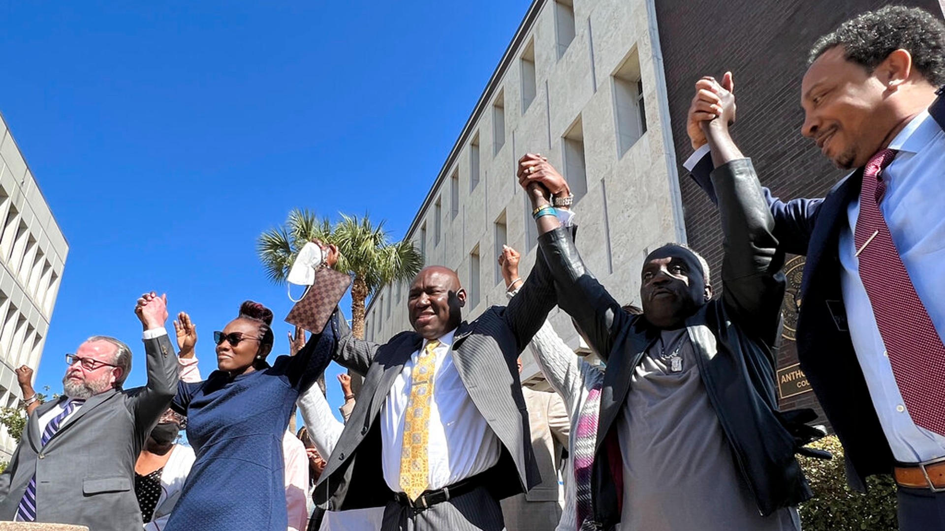 The family and attorneys of the Ahmaud Aubery raise their arms in victory after all three men were found guilty of hates crimes at the federal courthouse in Brunswick, Ga., on Tuesday, Feb. 22, 2022. (AP Photo/Lewis M. Levine)