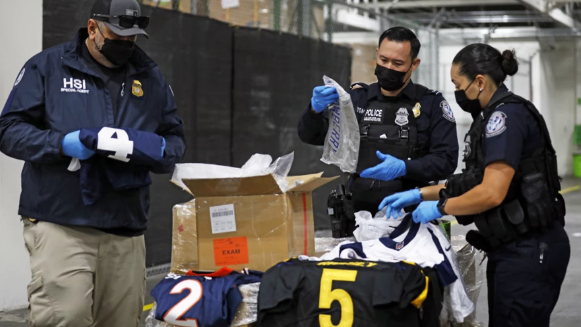 U.S. Customs and Border Protection officers open boxes of counterfeit sports-themed goods the agency has recovered.(Carolyn Cole / Los Angeles Times)