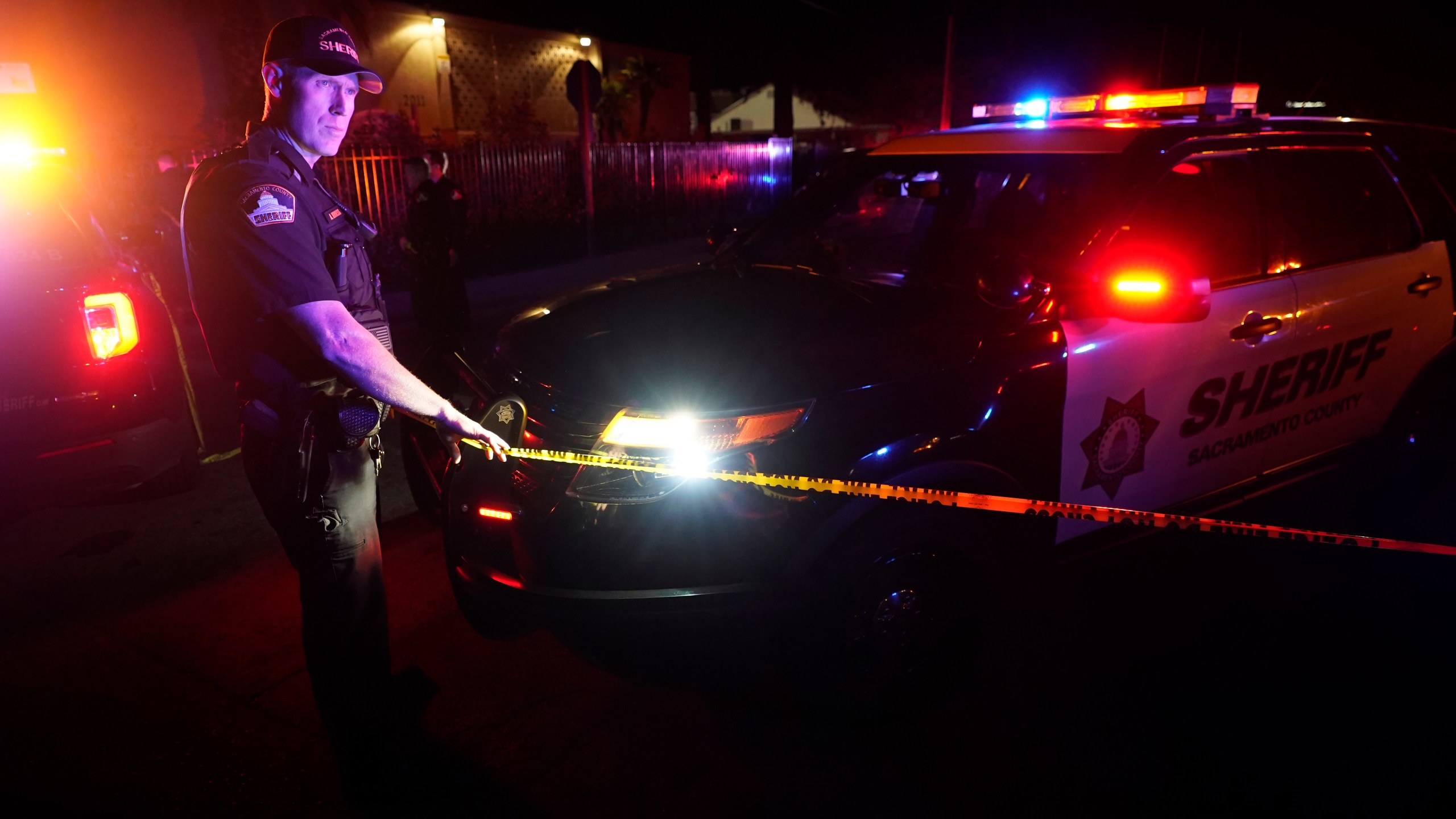 A Sacramento County Sheriff's deputy puts up police tape that blocks the street leading to a church where a fatal shooting occurred with multiple victims, in Sacramento, Calif., late Monday, Feb. 28, 2022. (AP Photo/Rich Pedroncelli)