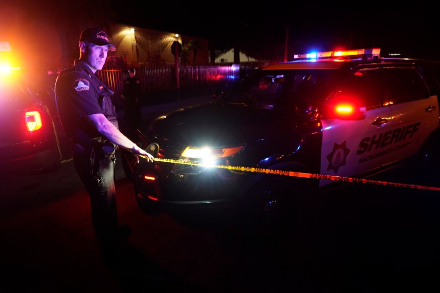 A Sacramento County Sheriff's deputy puts up police tape that blocks the street leading to a church where a fatal shooting occurred with multiple victims, in Sacramento, Calif., late Monday, Feb. 28, 2022. (AP Photo/Rich Pedroncelli)