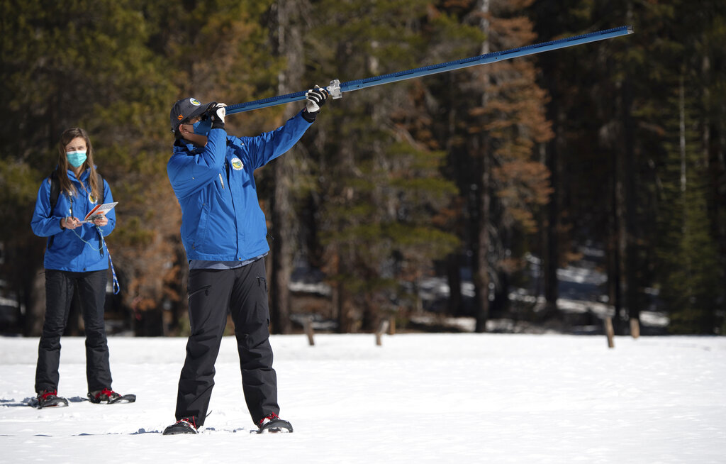 In this photo provided by the California Department of Water Resources, Lauren Alkire, left, and Sean de Guzman, manager of snow surveys and Water Supply Forecasting Unit, conduct the third snow survey of the season at Phillips Station near Echo Summit, Calif., on March 1, 2022. California's winter mountain snowpack is far below average after two historically dry months that reversed the gains from storms late last year, officials said Tuesday as they urged the nation's most populous state to conserve water. (Kenneth James/California Department of Water Resources via AP)