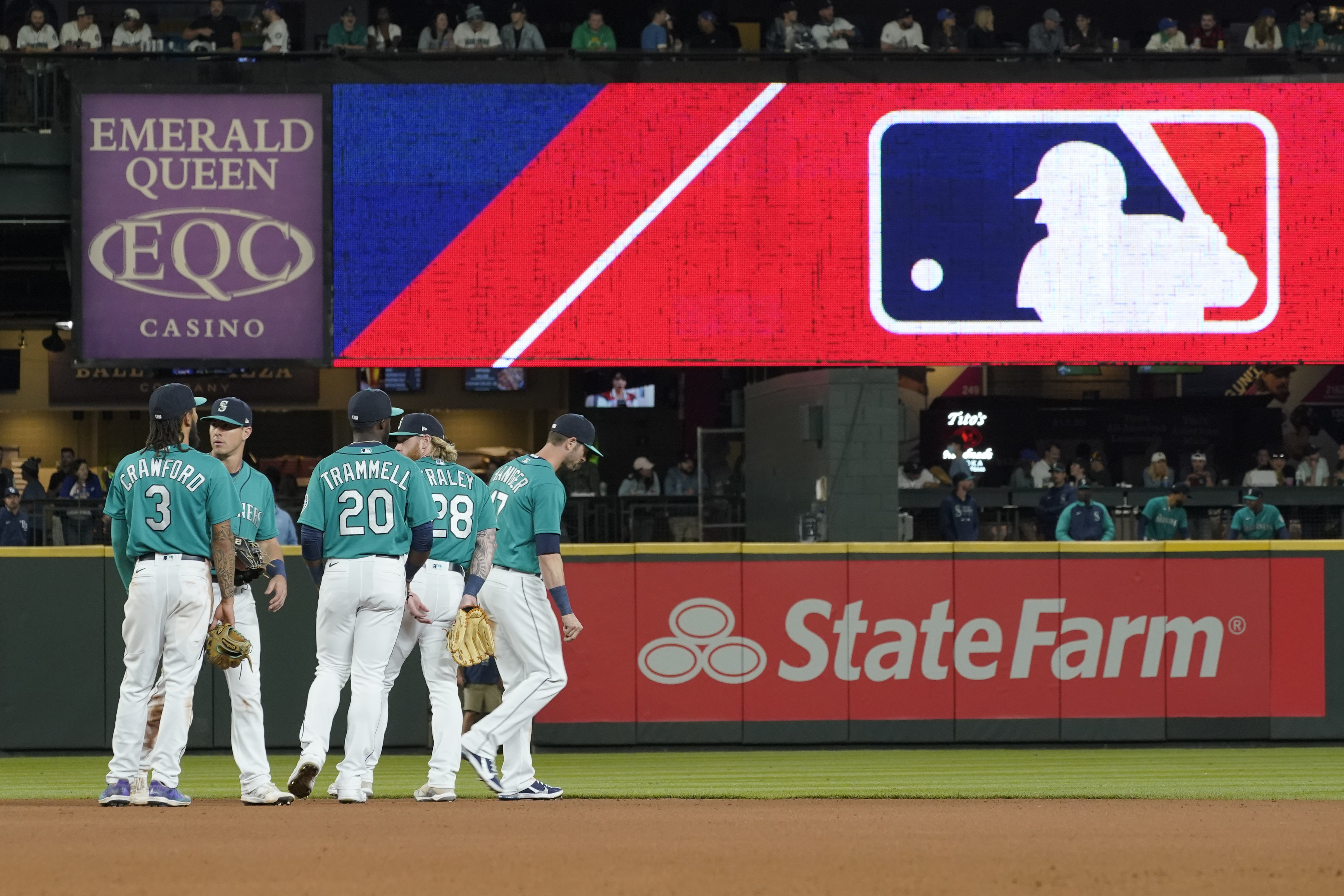 Seattle Mariners gather as the MLB logo is shown during a review of an attempted catch by right fielder Mitch Haniger of a ball hit by Tampa Bay Rays' Ji-Man Choi that was originally called an out during the ninth inning of a baseball game on June 18, 2021 in Seattle. (Ted S. Warren/Associated Press)