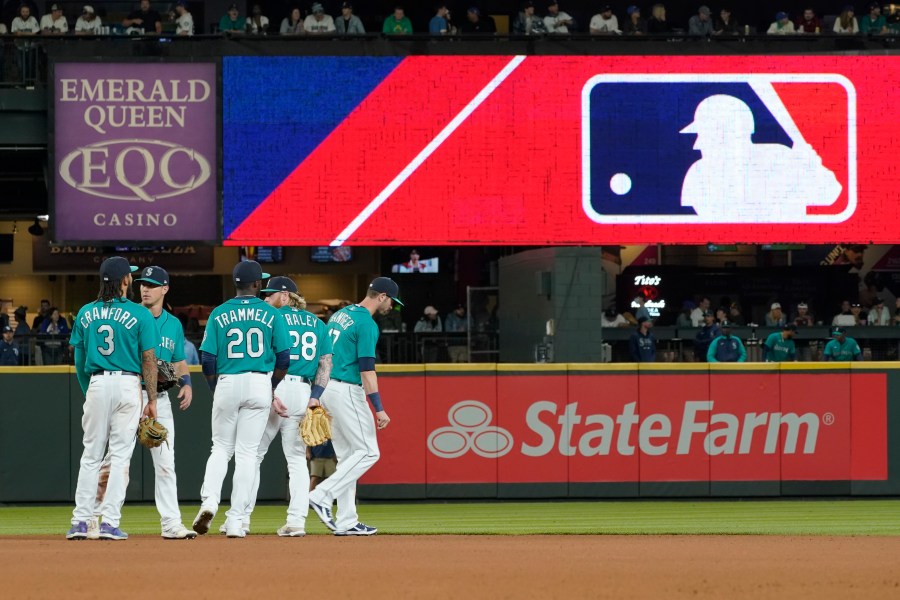 Seattle Mariners gather as the MLB logo is shown during a review of an attempted catch by right fielder Mitch Haniger of a ball hit by Tampa Bay Rays' Ji-Man Choi that was originally called an out during the ninth inning of a baseball game on June 18, 2021 in Seattle. (Ted S. Warren/Associated Press)