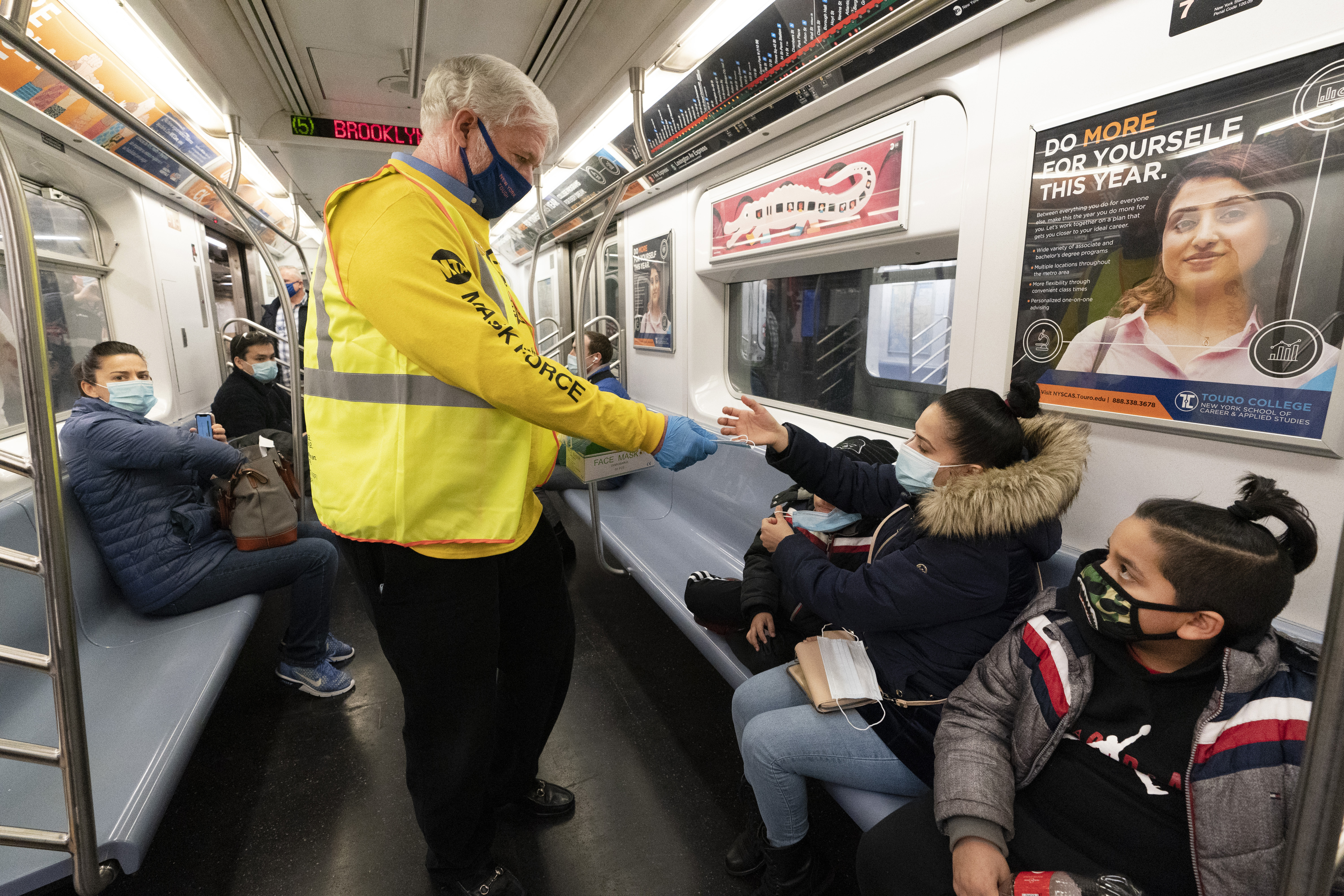 Patrick Foye, Chairman and CEO of the Metropolitan Transportation Authority, hands out face masks on a New York City subway, , Nov. 17, 2020, in New York. The Centers for Disease Control and Prevention is developing guidance that will ease the nationwide mask mandate for public transit next month. That's according to a U.S. official. (AP Photo/Mark Lennihan, File)