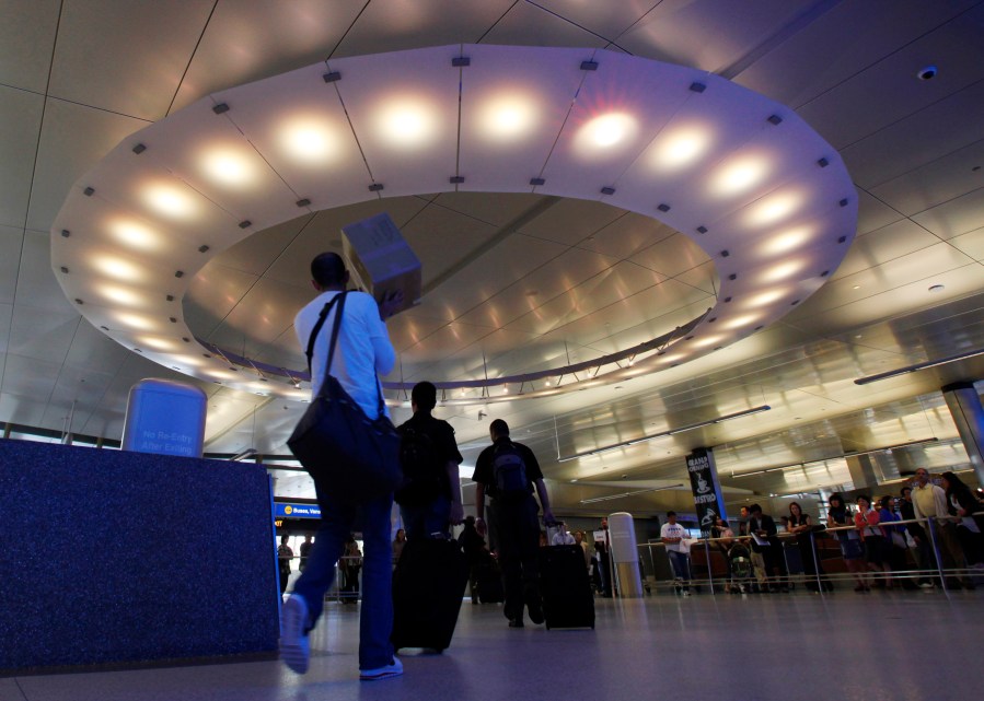 Arriving international passengers pass under a large "halo" of light in the area where they meet friends and family, at the customs clearance area at the Tom Bradley International Terminal at Los Angeles International Airport, May 28, 2010. Three Muslim Americans have filed a lawsuit alleging that U.S. border officers questioned them about their religious beliefs in violation of their constitutional rights when they returned from international travel. The three men from Minnesota, Texas and Arizona sued Department of Homeland Security officials on Thursday, March 24, 2022, in a federal court in Los Angeles. The suit was filed in California because some of the questioning allegedly occurred at Los Angeles International Airport. (AP Photo/Reed Saxon, File)