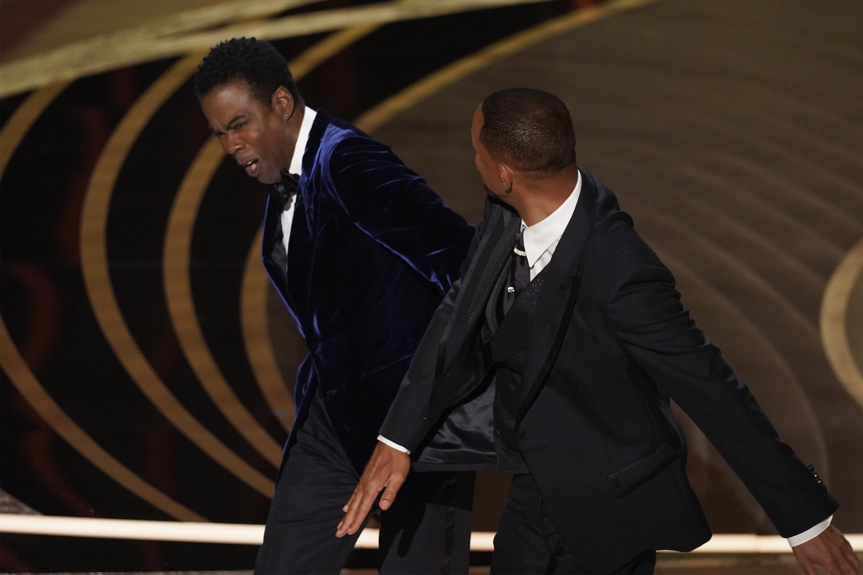 Will Smith, right, hits presenter Chris Rock on stage while presenting the award for best documentary feature at the Oscars on Sunday, March 27, 2022, at the Dolby Theatre in Los Angeles. (AP Photo/Chris Pizzello)