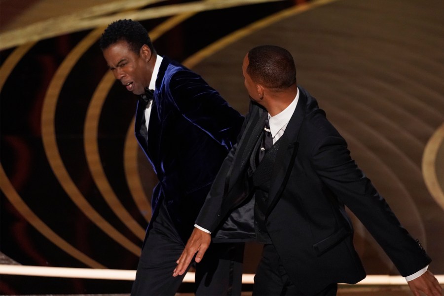 Will Smith, right, hits presenter Chris Rock on stage while presenting the award for best documentary feature at the Oscars on Sunday, March 27, 2022, at the Dolby Theatre in Los Angeles. (AP Photo/Chris Pizzello)