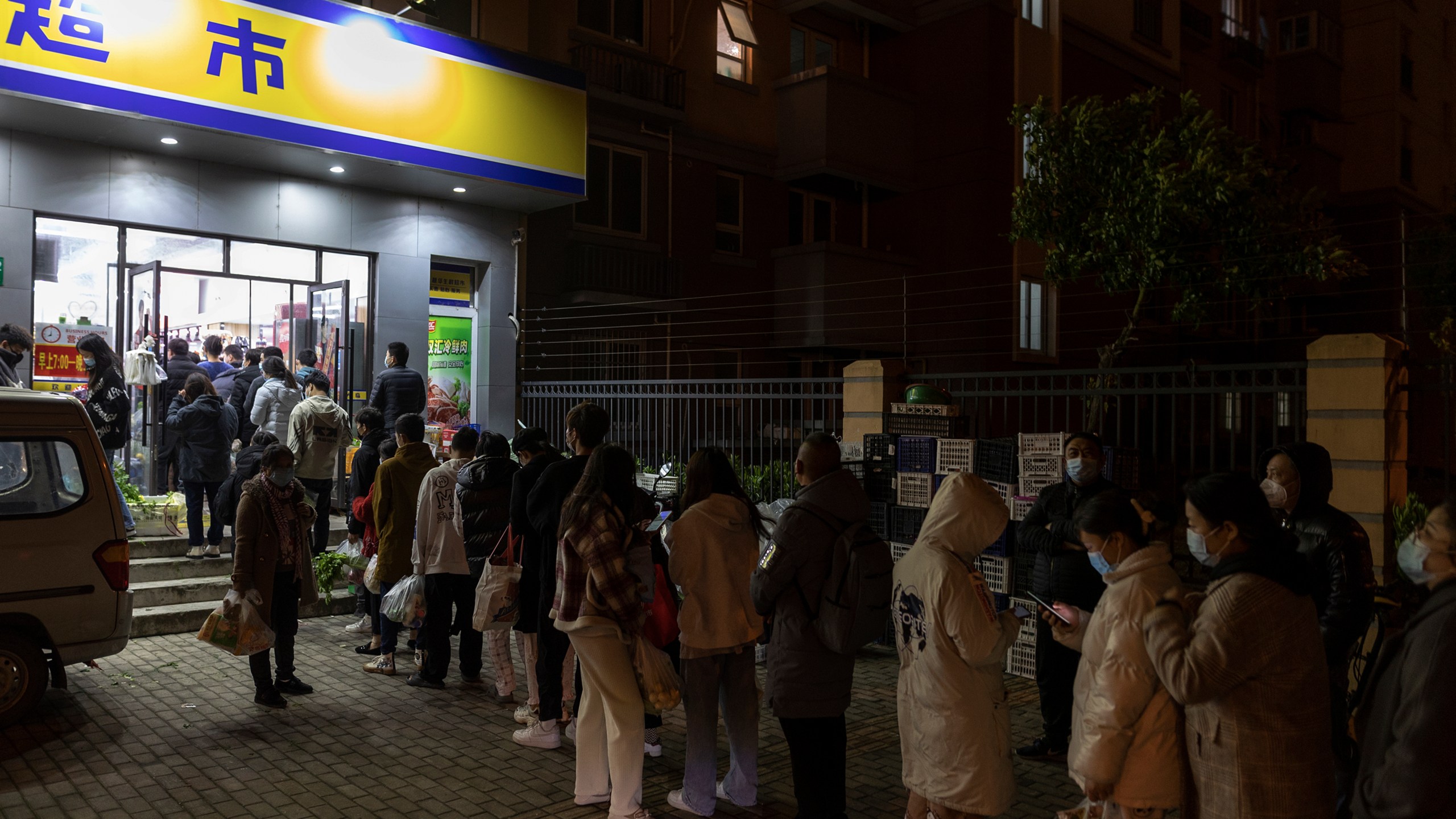 Residents wearing face masks to help protect from the coronavirus line up outside a supermarket at night to buy groceries on Sunday, March 27, 2022, in Shanghai, China. China began locking down most of its largest city of Shanghai on Monday as part of its strict COVID-19 strategy, amid questions over the policy's economic toll on the country. (AP Photo)