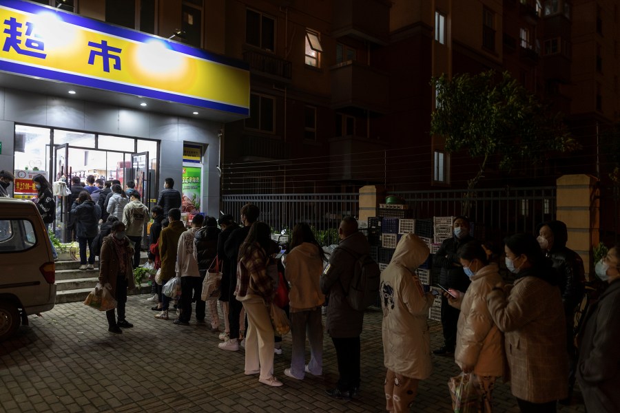 Residents wearing face masks to help protect from the coronavirus line up outside a supermarket at night to buy groceries on Sunday, March 27, 2022, in Shanghai, China. China began locking down most of its largest city of Shanghai on Monday as part of its strict COVID-19 strategy, amid questions over the policy's economic toll on the country. (AP Photo)