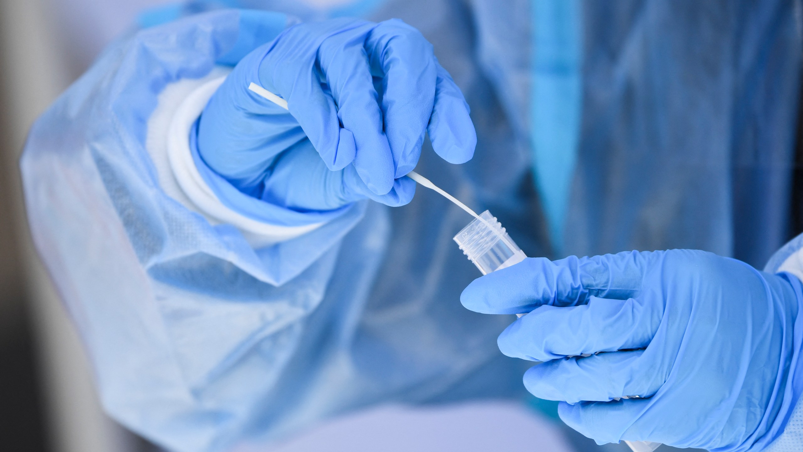 A health care worker places a test swab into solution for a PCR Covid-19 test at a testing site in Hawthorne, California on Jan. 18, 2022. (PATRICK T. FALLON/AFP via Getty Images)